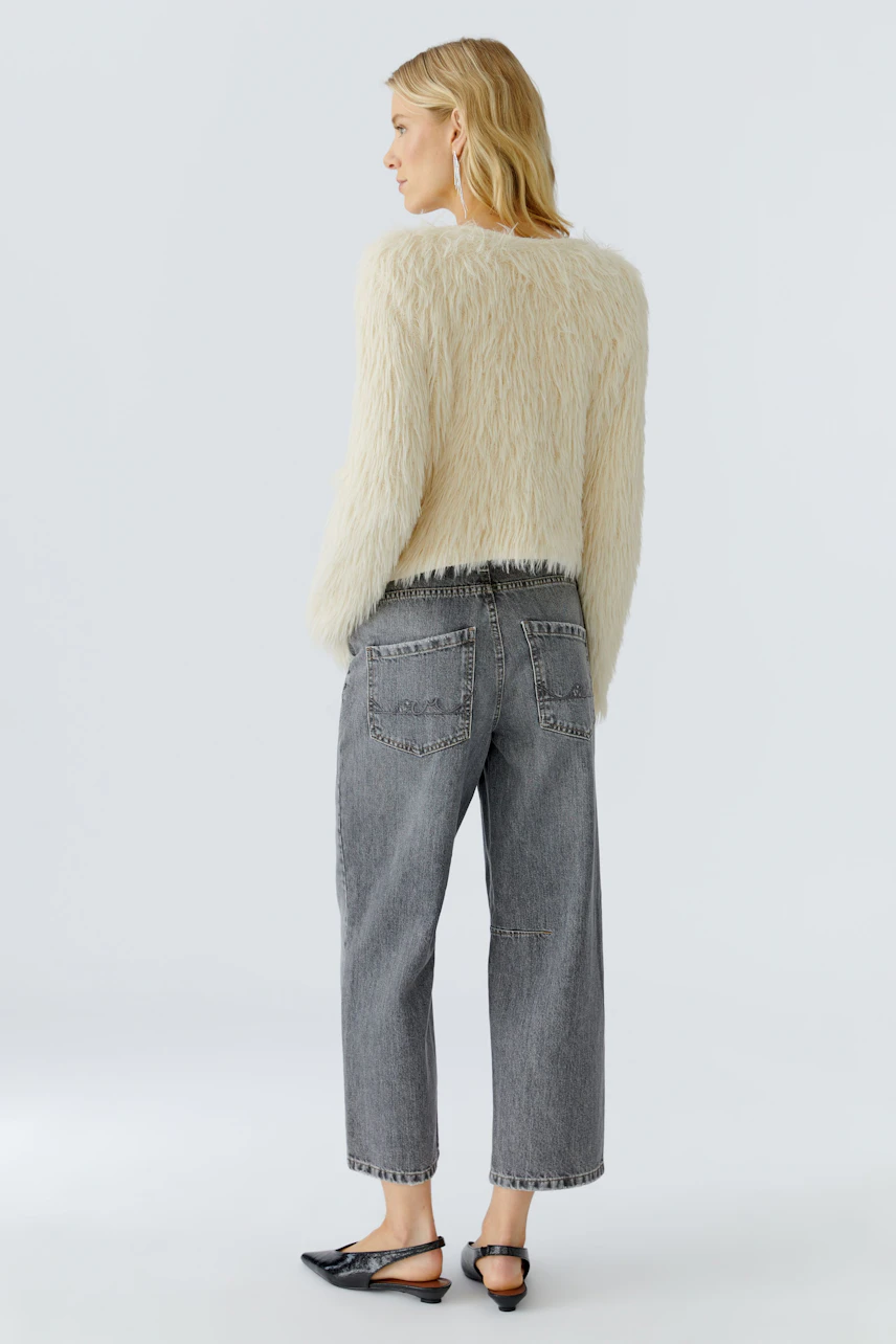 Casual women's cardigan: A woman in a fluffy cream cardigan paired with relaxed-fit jeans.