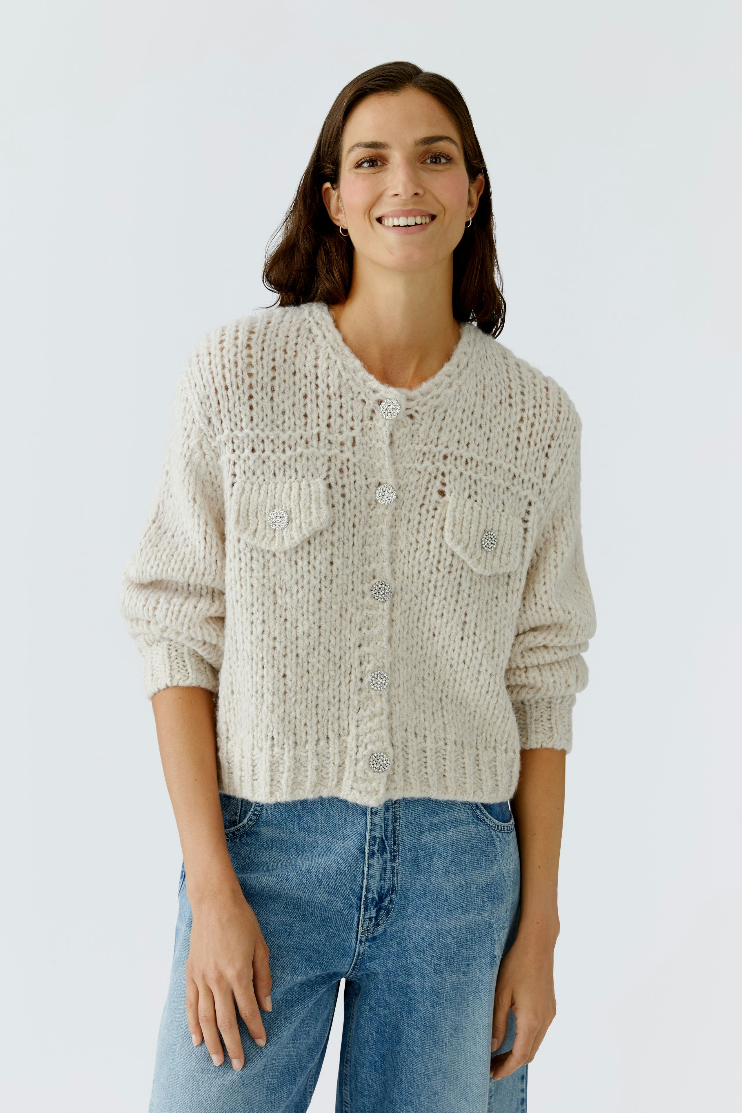Bequeme Damen-Strickjacke: Frau in heller Strickjacke mit Knöpfen und zwei Brusttaschen lächelt.