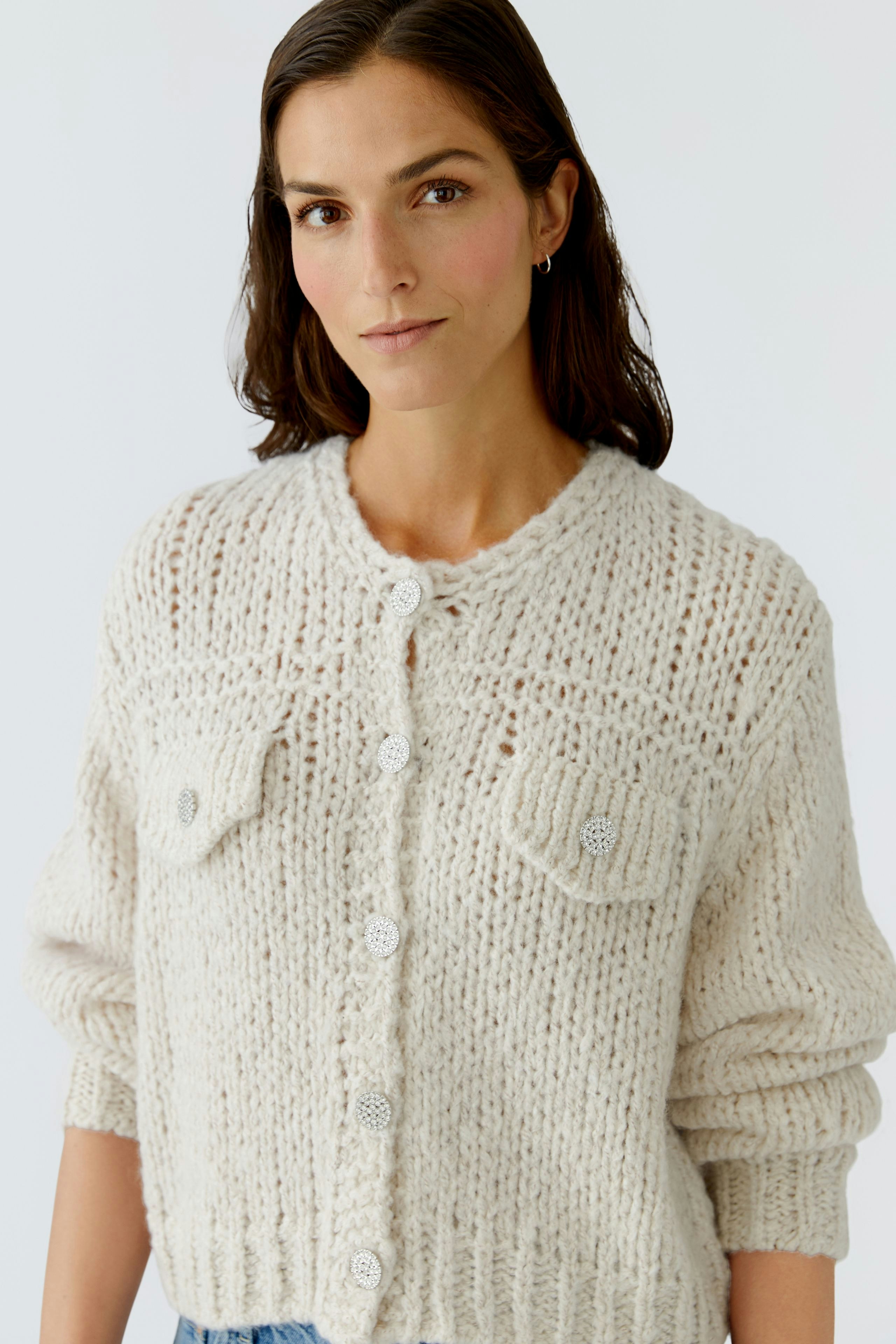 Bequeme Damen-Strickjacke: Frau in einer hellen, grob gestrickten Jacke mit Knöpfen und Taschen.