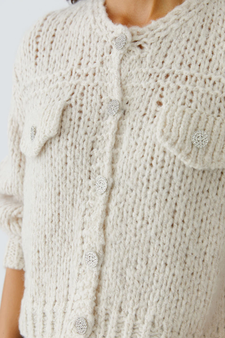 Casual women's cardigan: A woman in a cozy cream cardigan with button details and pockets.