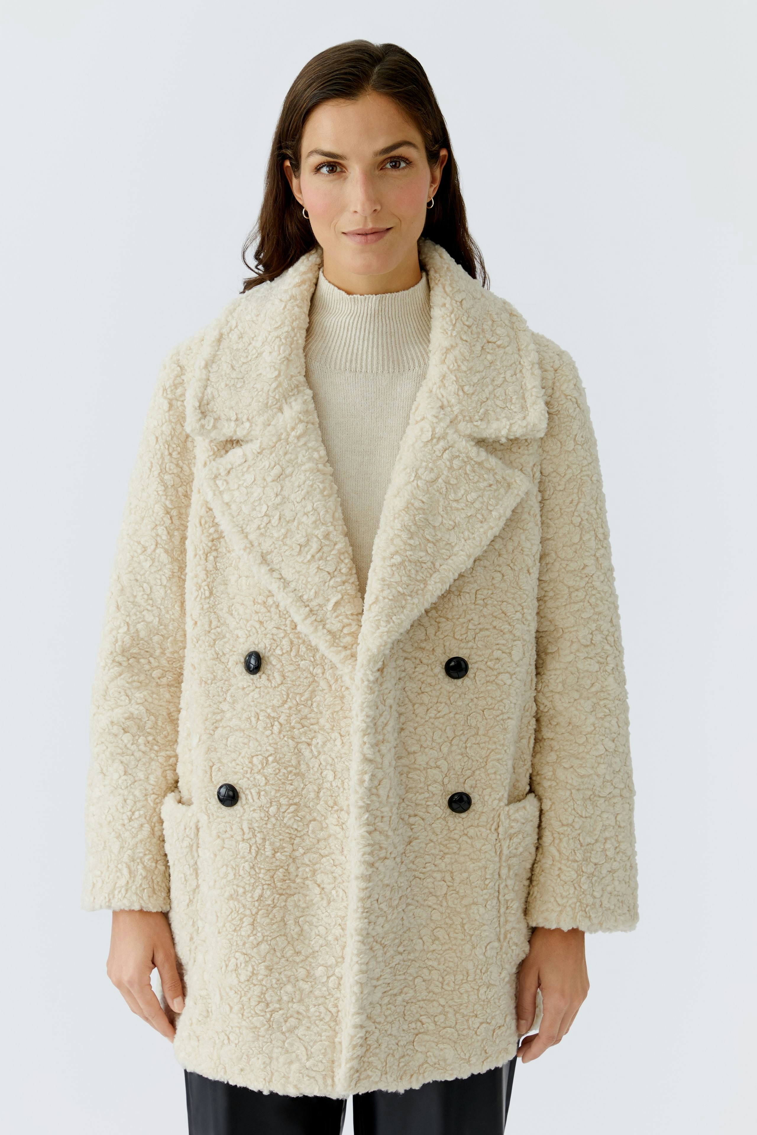 Cozy women's coat: A woman in a soft, cream-colored double-breasted coat with large buttons.