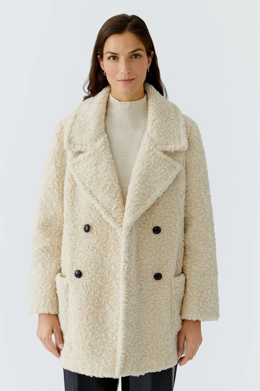 Cozy women's coat: A woman in a soft, cream-colored double-breasted coat with large buttons.