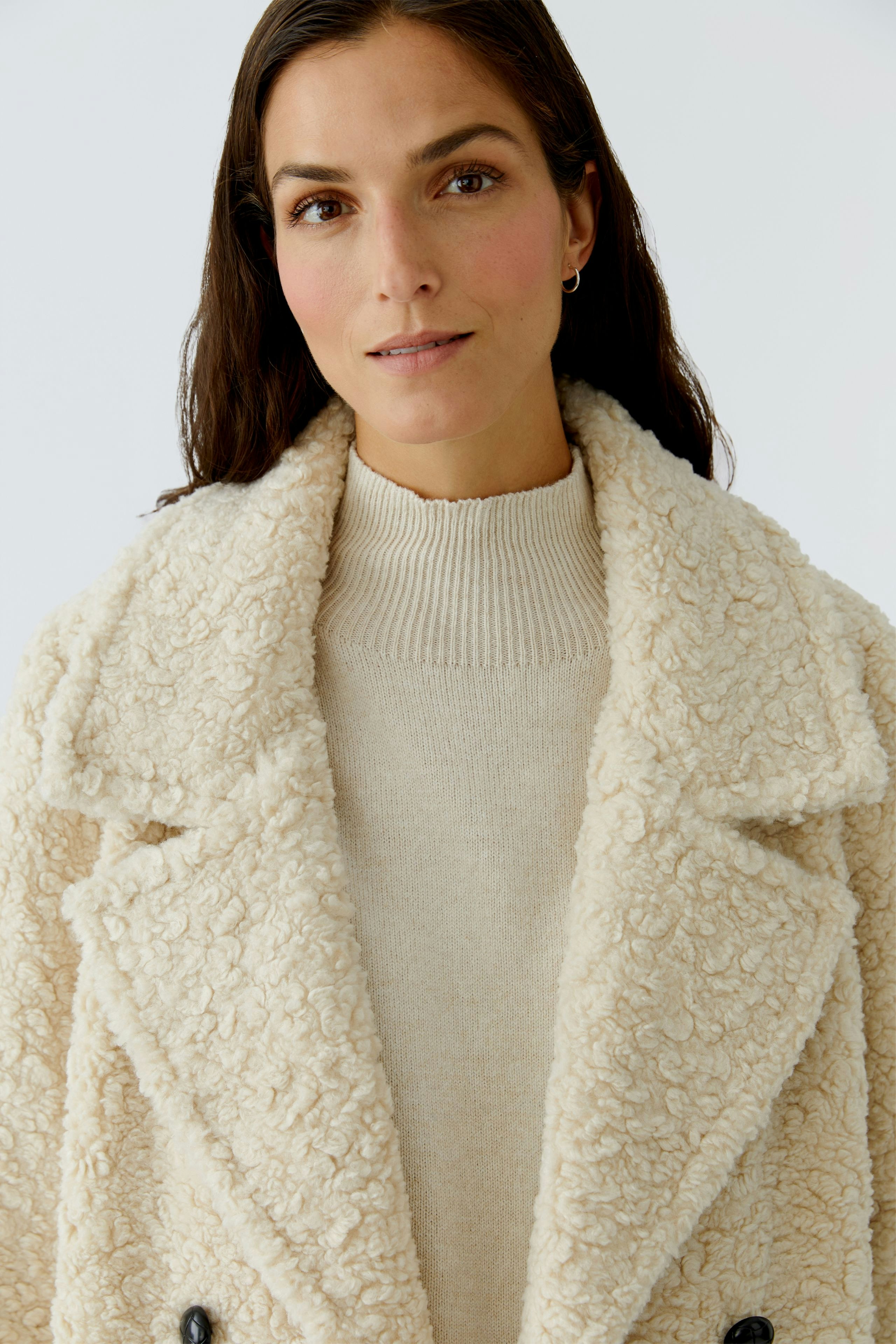 Cozy women's coat: A woman in a fluffy cream coat with a soft collar and buttons.