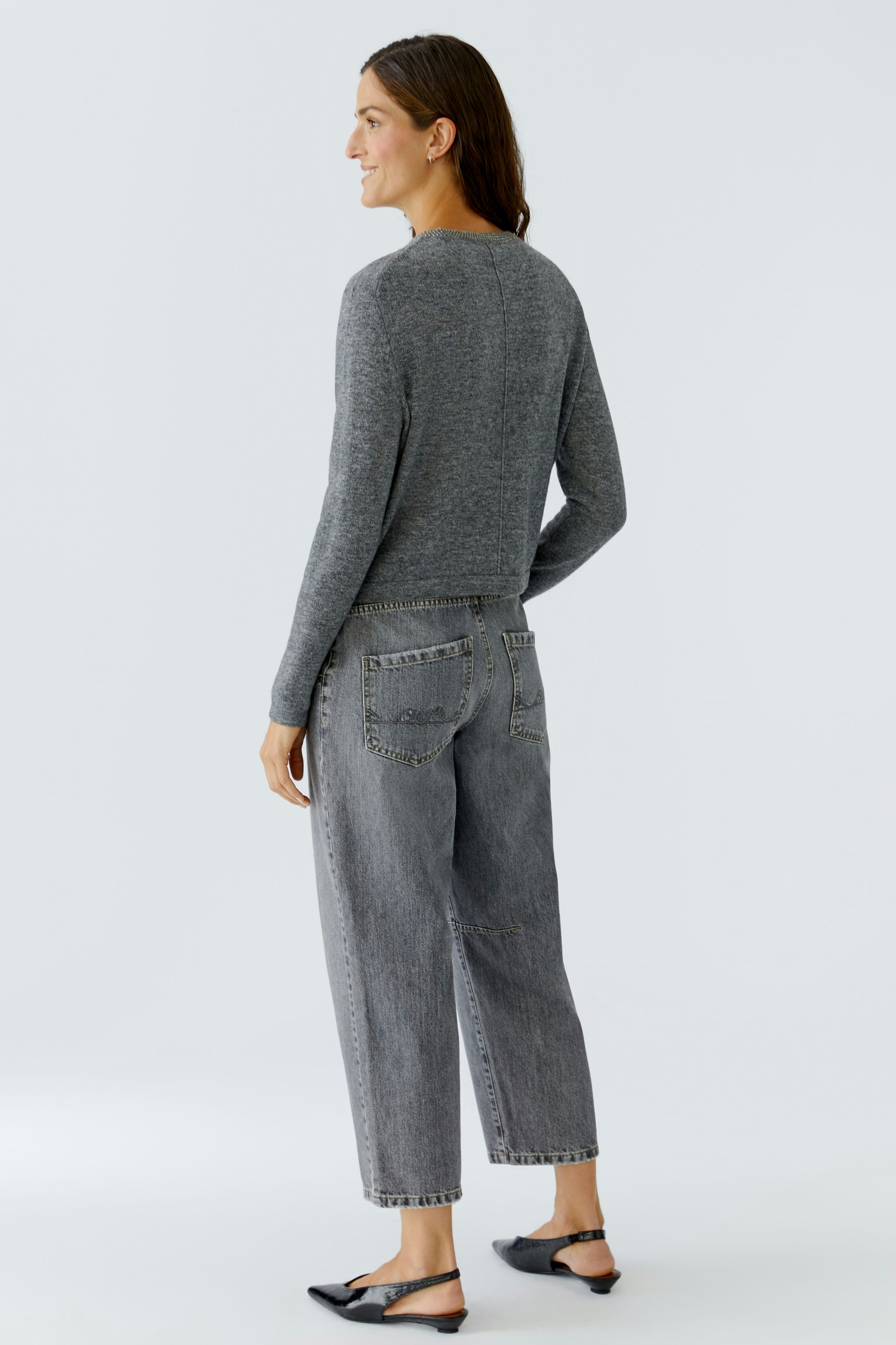 Casual women's pullover: A woman in a gray pullover with a relaxed fit, paired with loose jeans.