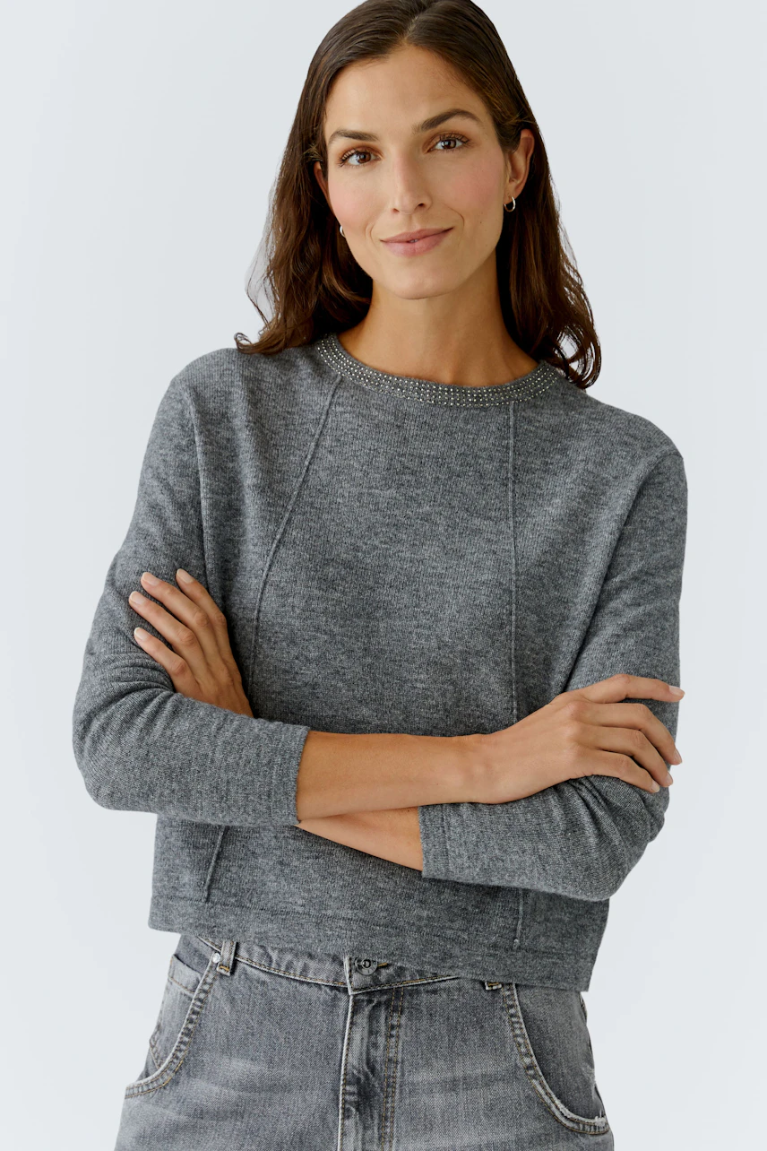 Damen-Pullover: Frau in grauem, lässigem Pullover mit Rundhalsausschnitt und lockerer Passform.