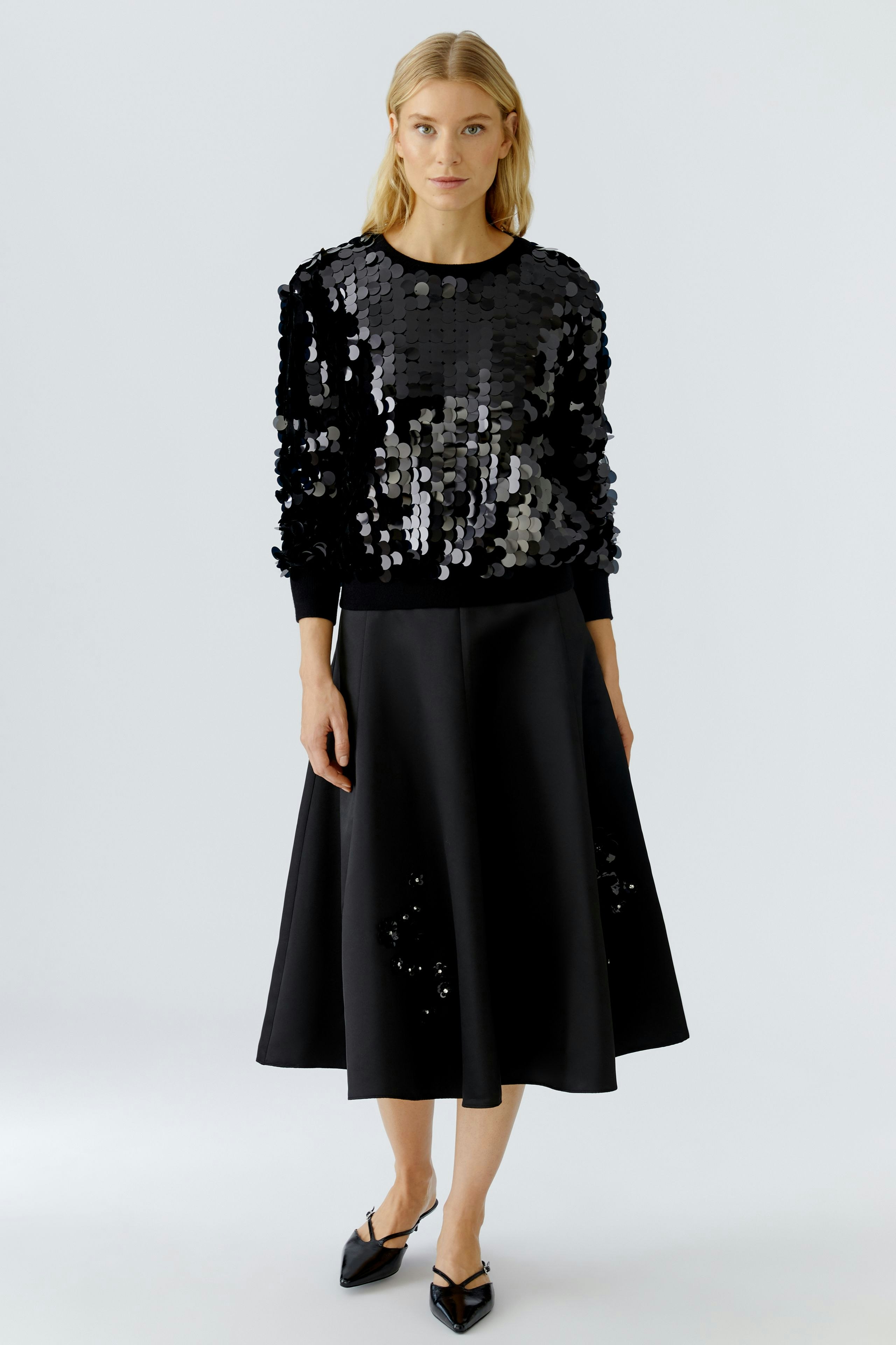 Stylish women's pullover: A woman in a black sequined pullover paired with a flowing skirt.