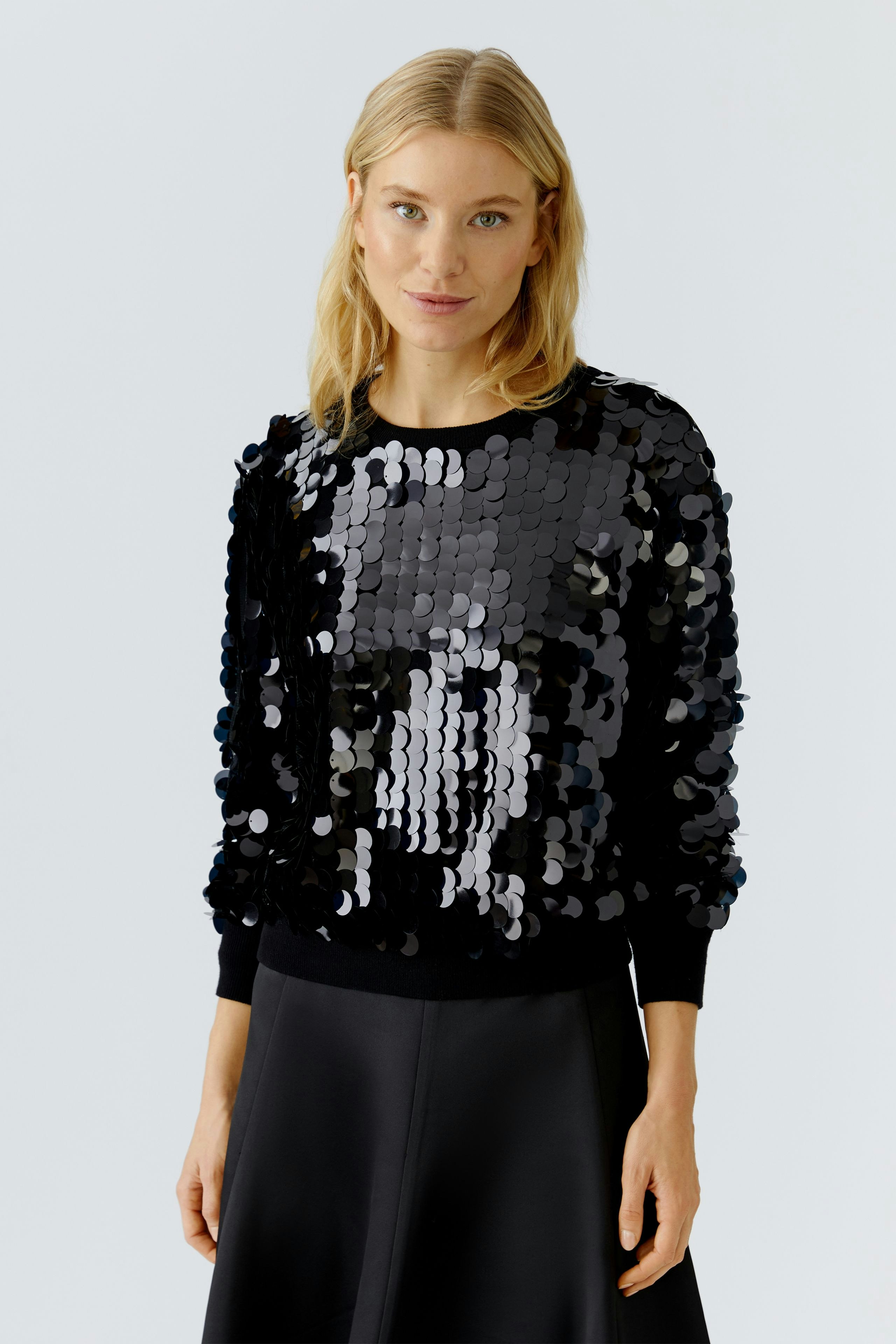 Modern women's pullover: A woman in a black sequined pullover with a relaxed fit.