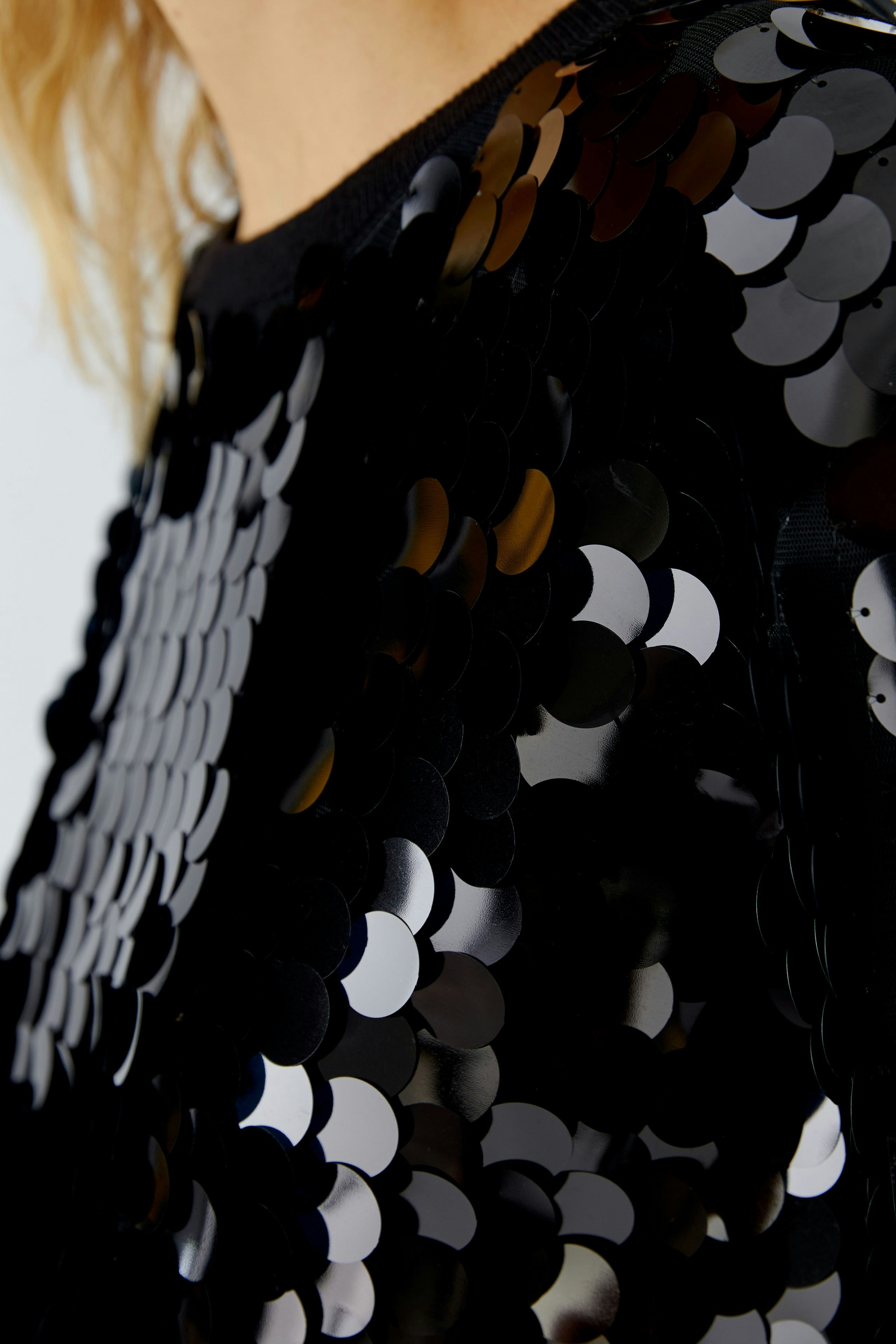 Stylish women's pullover: Close-up of a woman in a black sequined pullover, showcasing a trendy look.