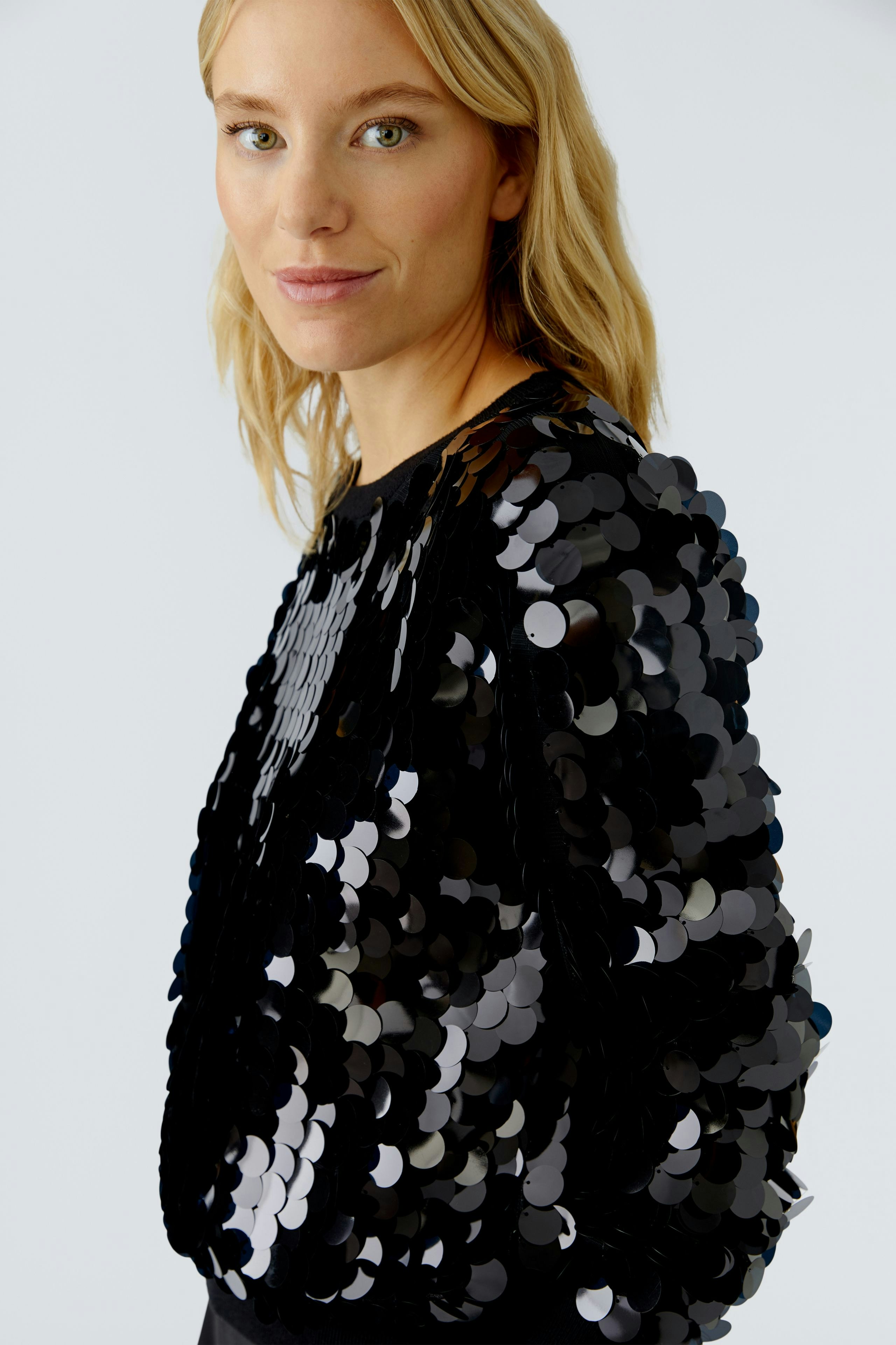 Trendy women's pullover: Woman in a black sequined pullover, showcasing a stylish and playful look.