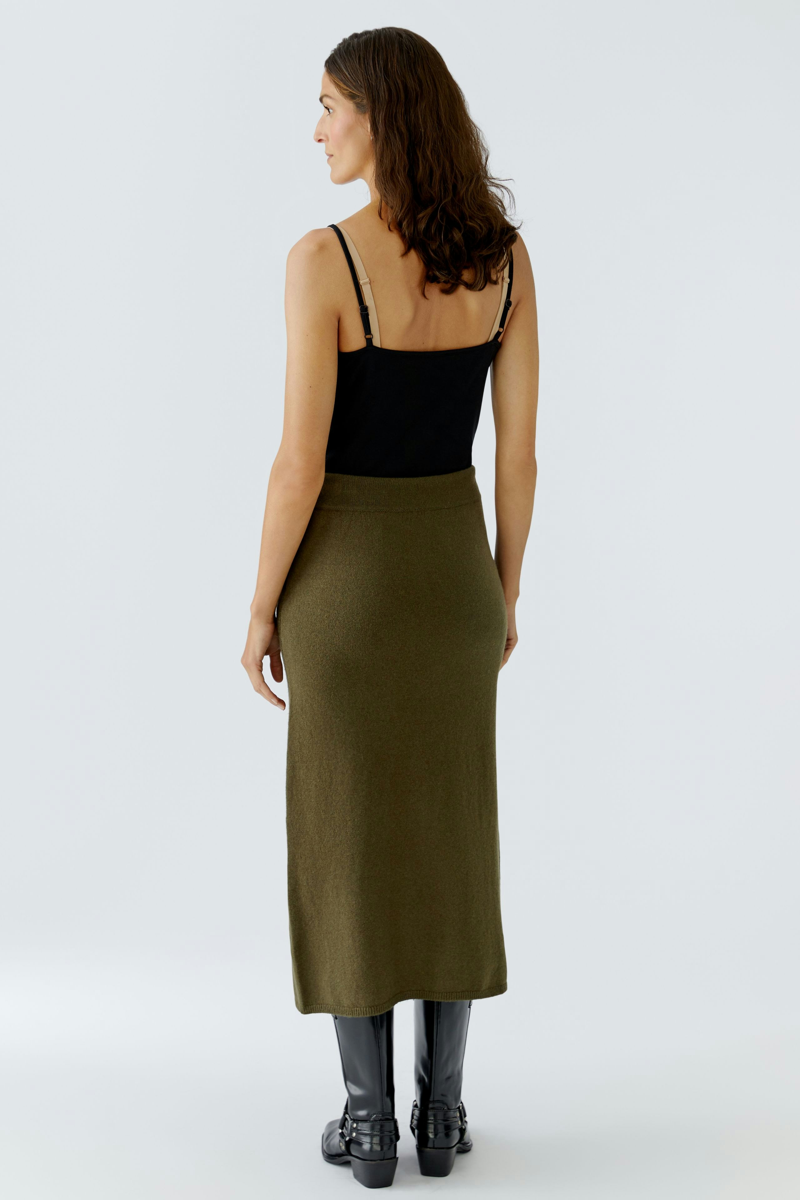 Casual women's knitted skirt: A woman in a fitted olive green skirt, showcasing a simple and modern style.