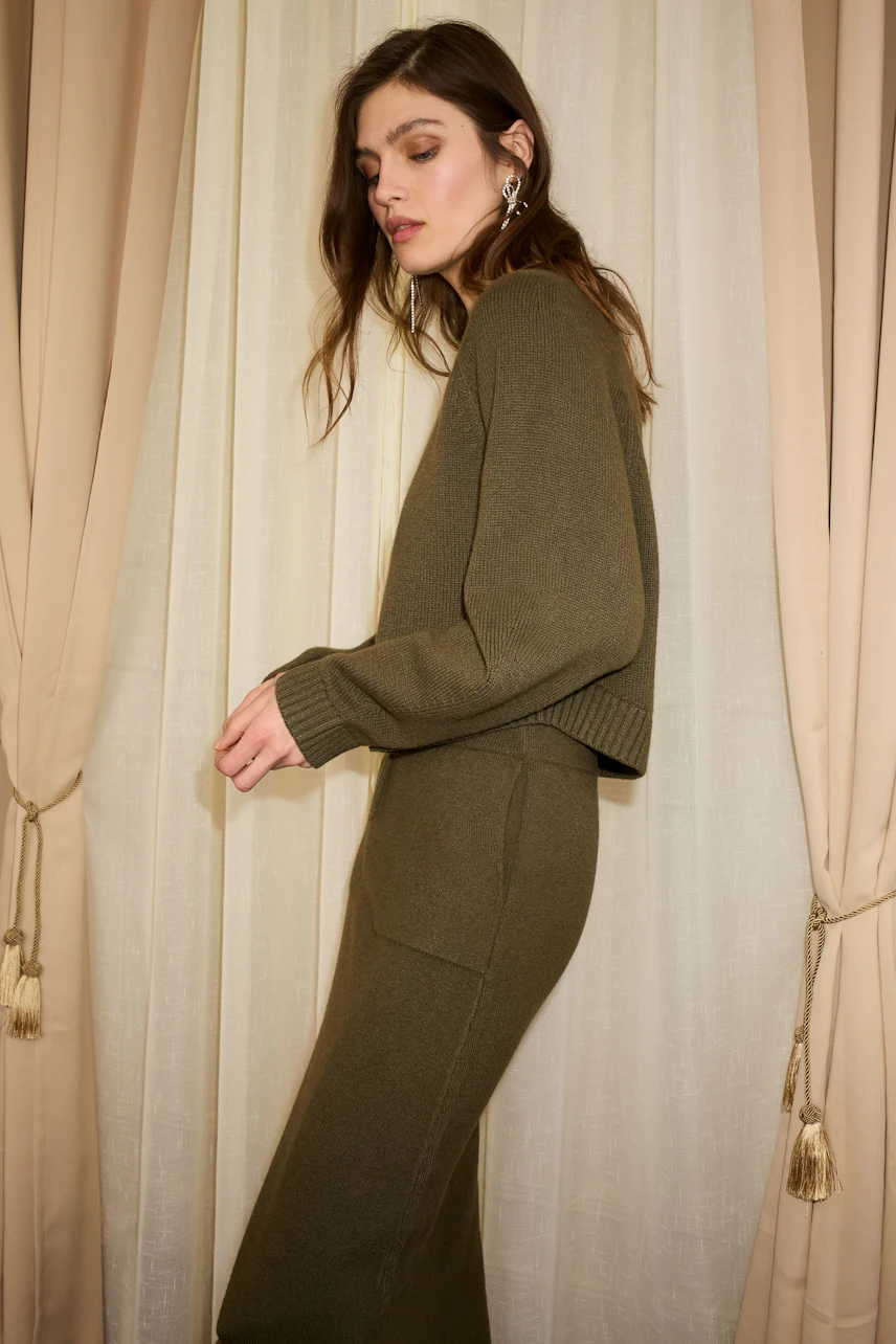 Casual women's knit skirt: A woman in an olive green knit skirt and matching pullover stands gracefully.