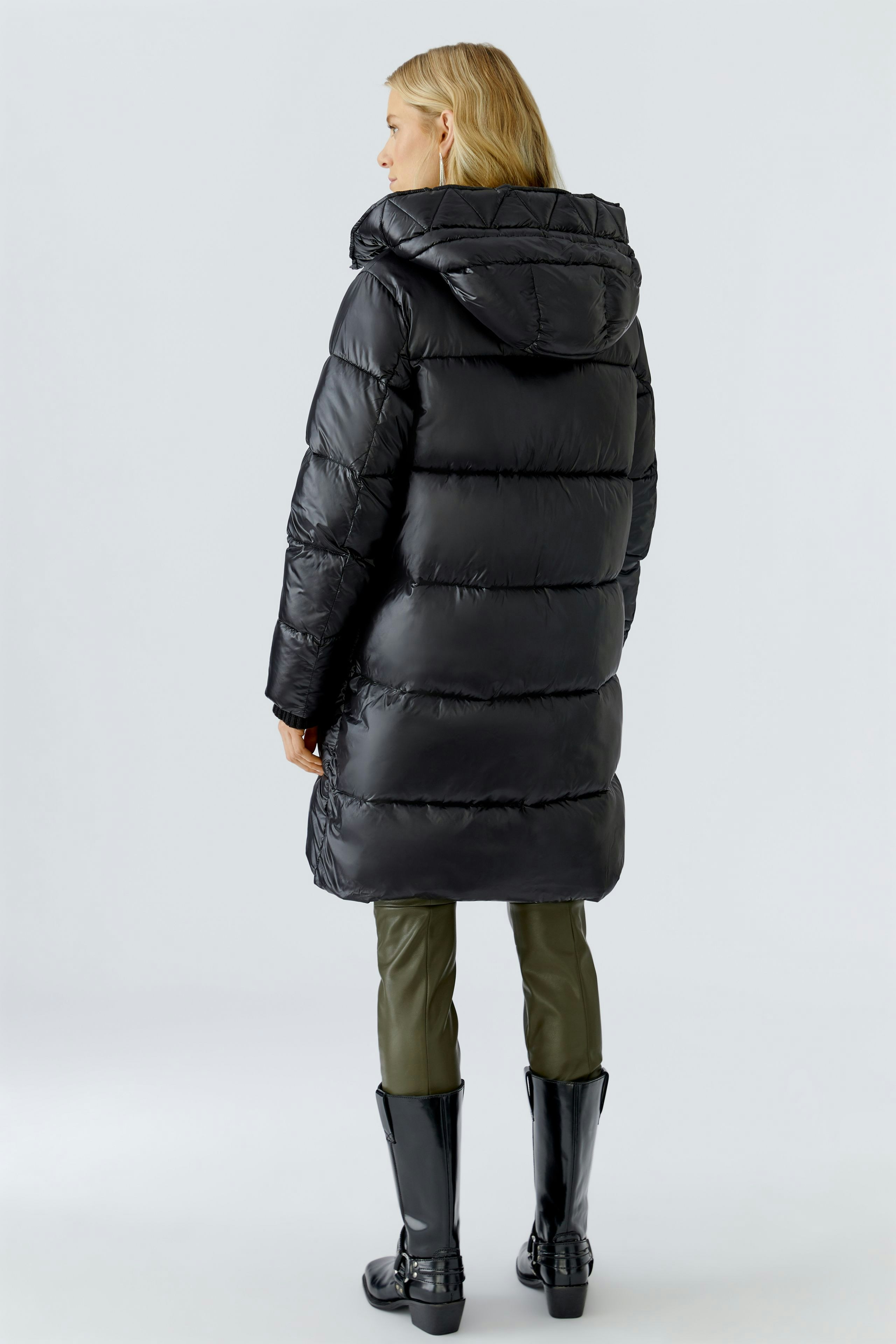 Stylish women's winter coat: A woman in a black puffer coat with a hood, showcasing a modern design.