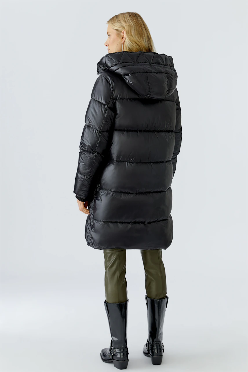 Stylish women's winter coat: A woman in a black puffer coat with a hood, showcasing a modern design.