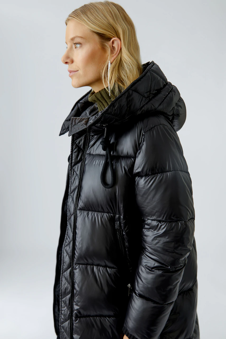 Stylish women's winter coat: Woman in a black puffer coat with a hood, ready for cold weather.