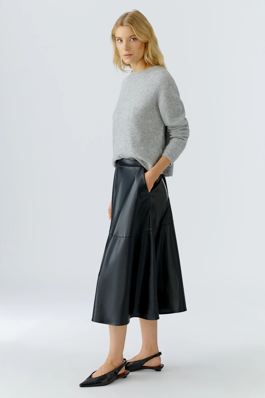 Damen-Pullover: Frau in grauem, lässigem Strickpullover mit Rundhalsausschnitt und schwarzem Rock.