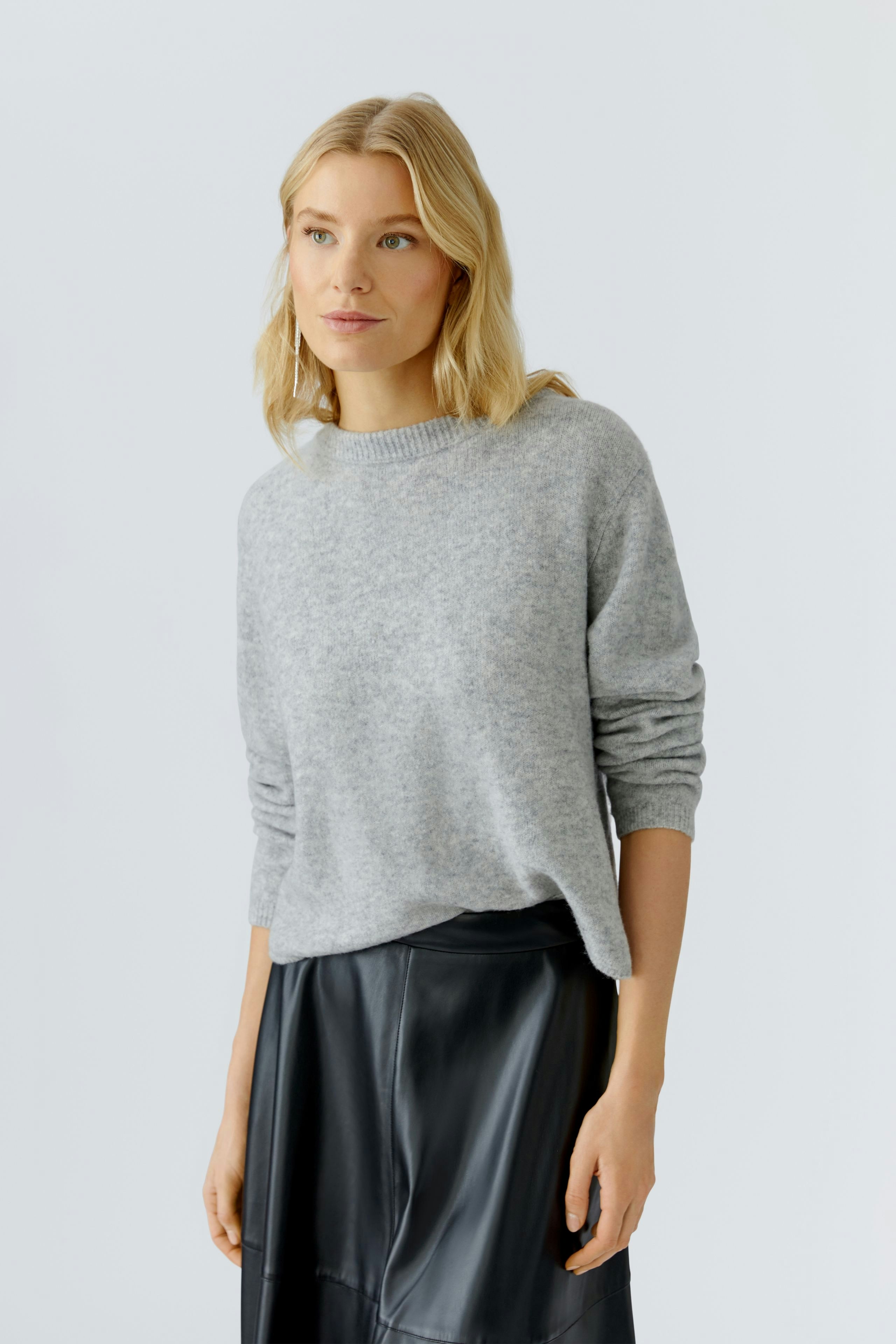 Casual women's pullover: Young woman in a light gray pullover paired with a black skirt.