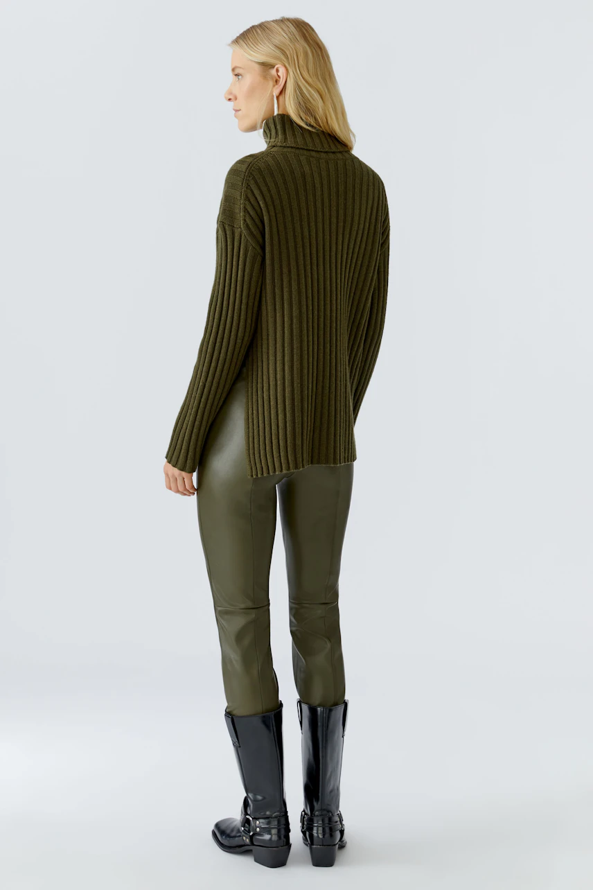 Casual women's pullover: A woman in a green ribbed pullover paired with sleek pants and stylish boots.