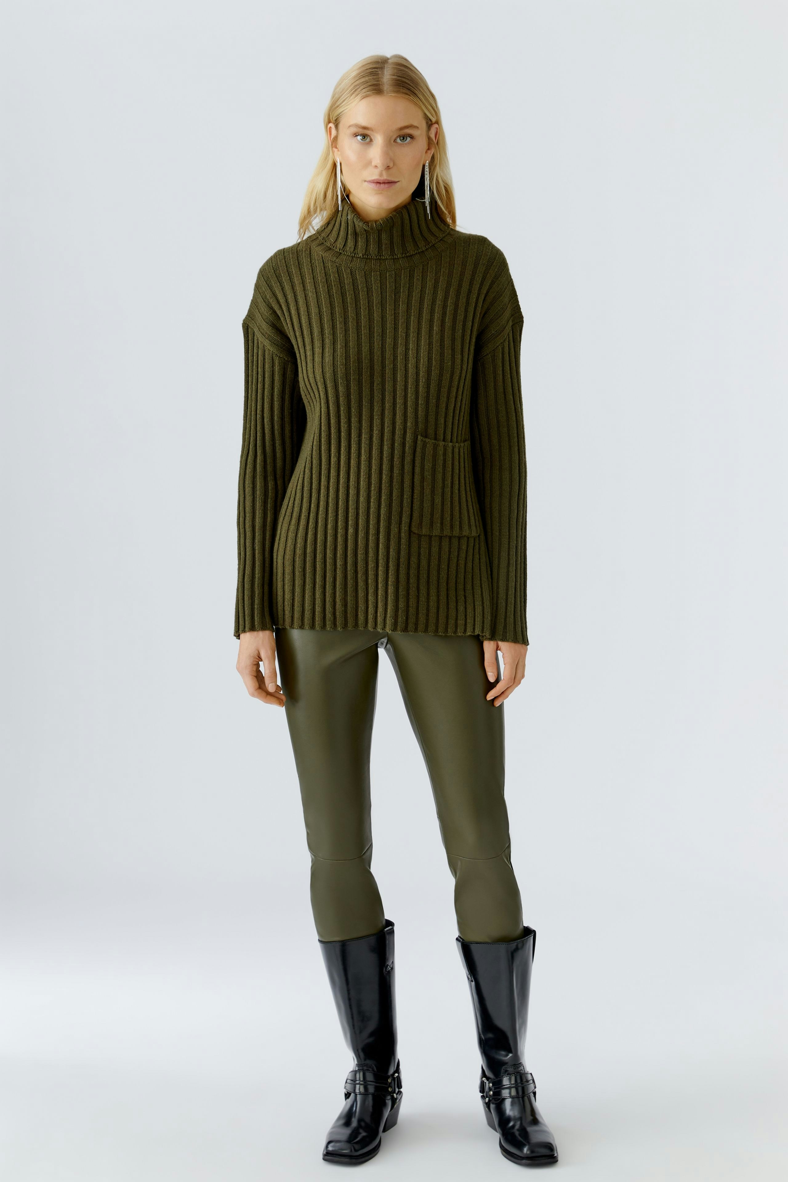 Damen-Pullover in Olivgrün: Frau trägt einen strukturierten Pullover mit hohem Kragen und praktischer Tasche.