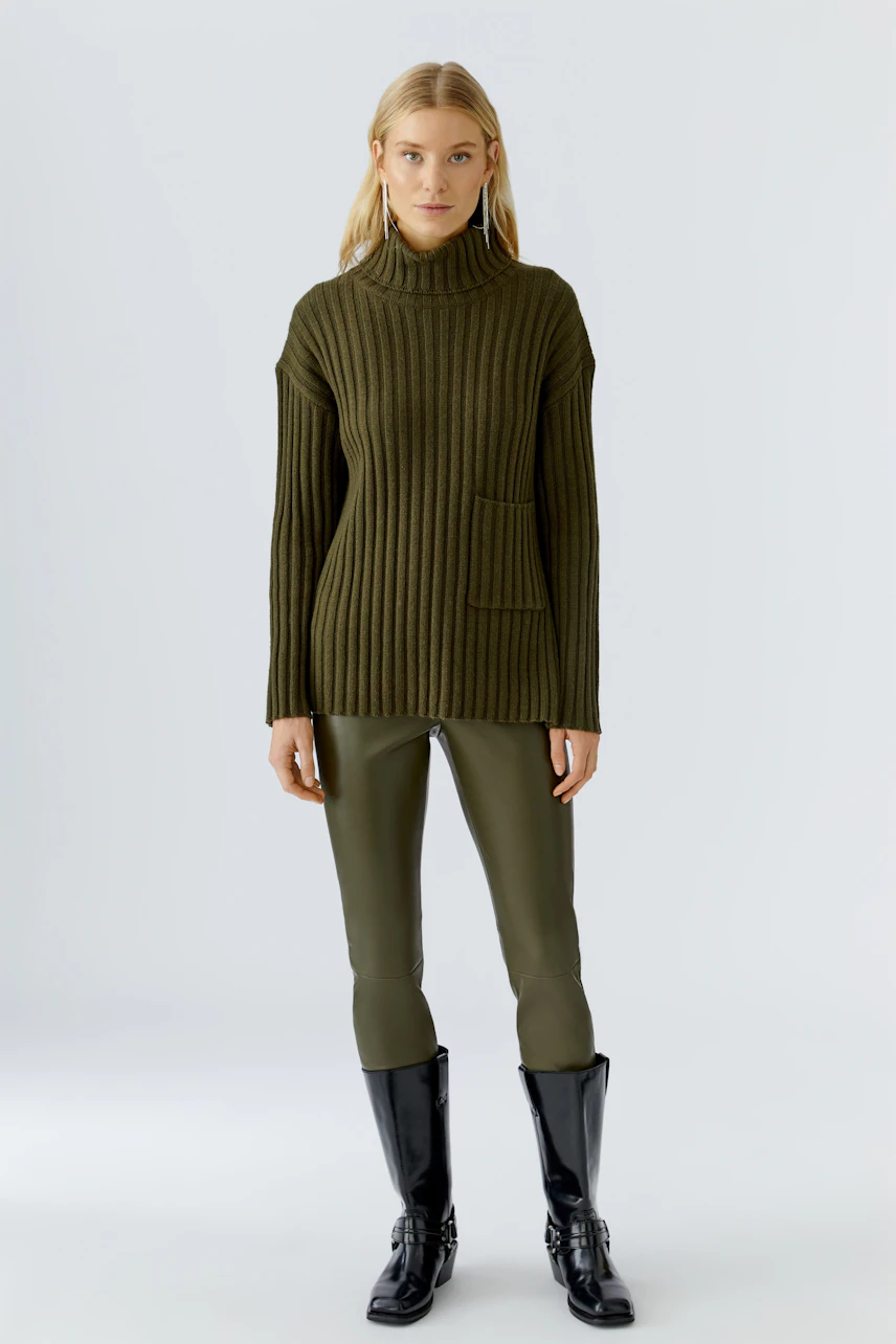 Casual women's pullover: A woman in a ribbed olive green pullover with a high collar and pocket.