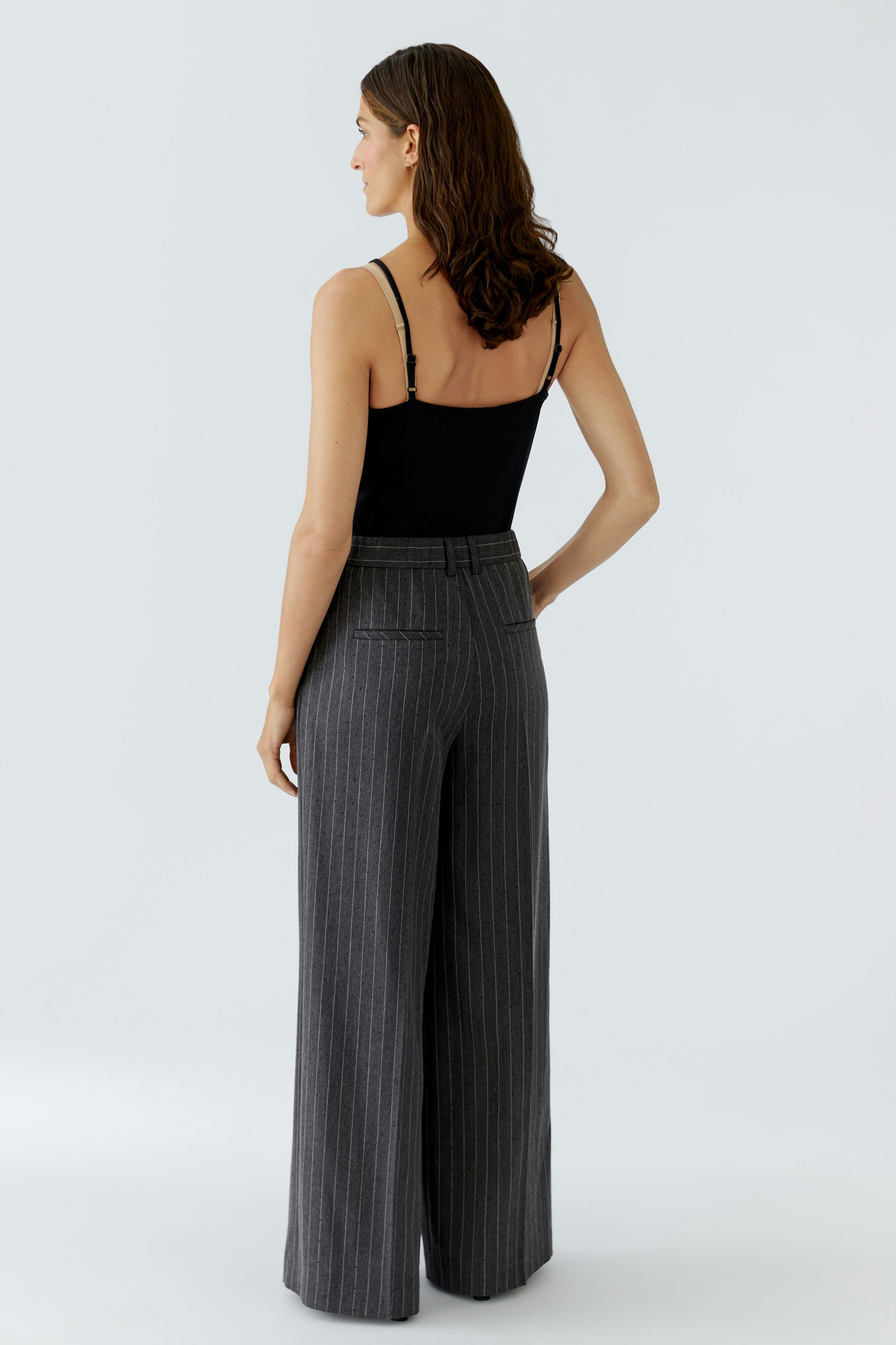 Stylish women's pleated trousers: A woman in striped pants with a fitted top, showcasing a relaxed fit.