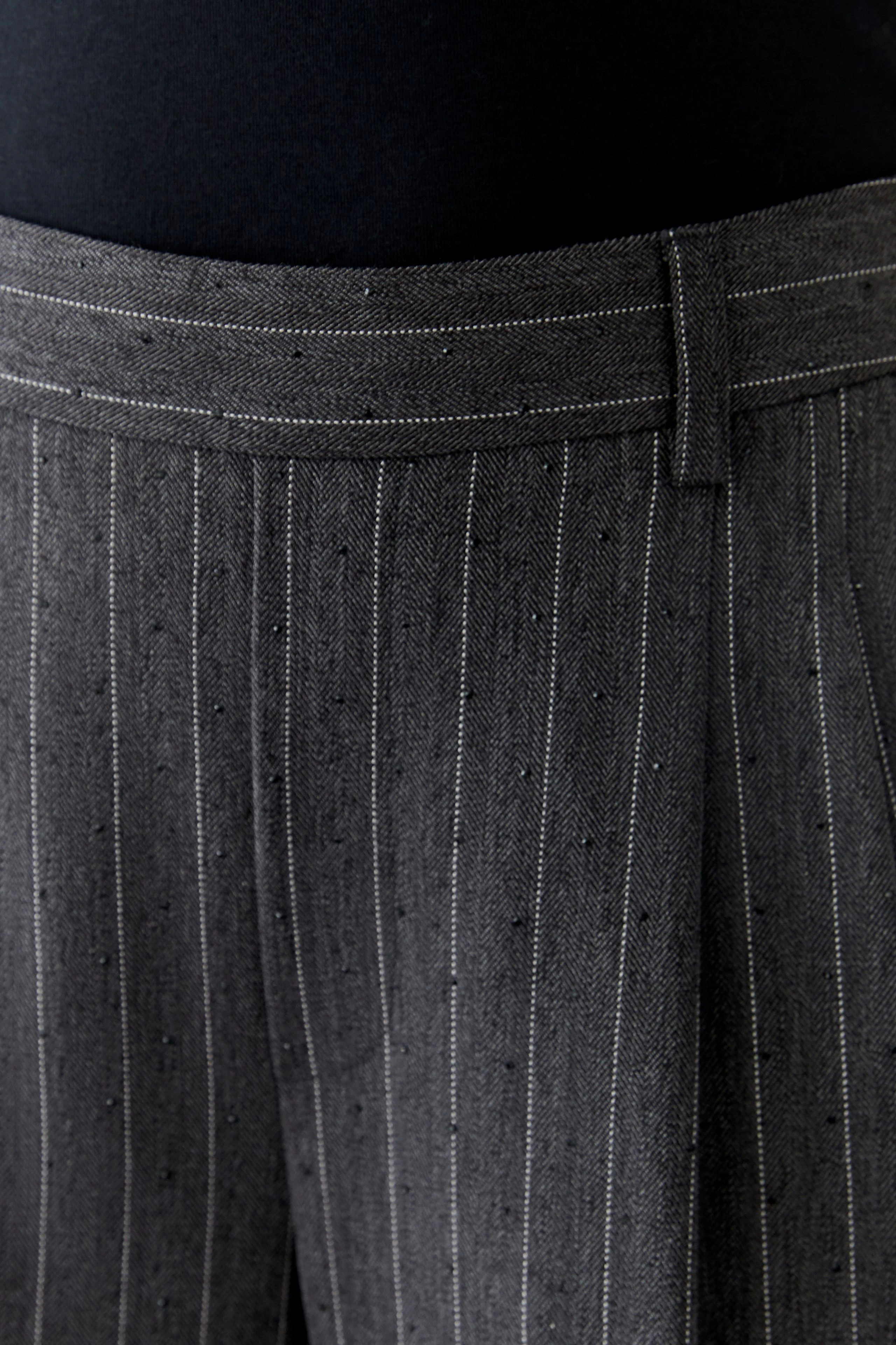 Bundfaltenhose: Dunkle Hose mit feinen Streifen, ideal für lässige Outfits.