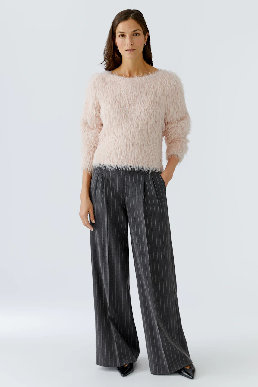 Casual women's pleated trousers: A woman in soft, fluffy pink pullover and striped wide-leg pants stands confidently.