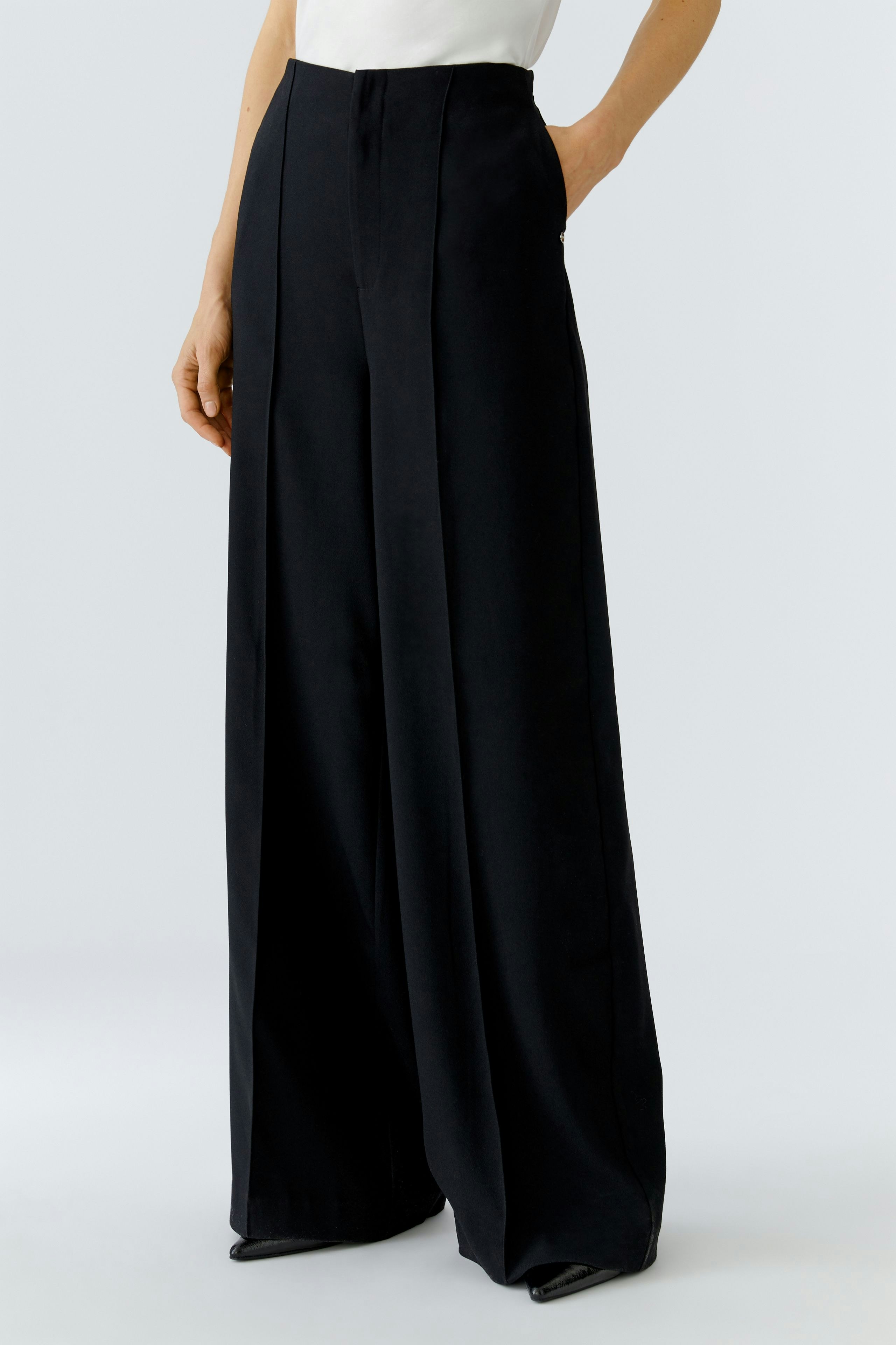 Wide-leg trousers: A woman in black Marlene trousers with a high waist and a relaxed fit.