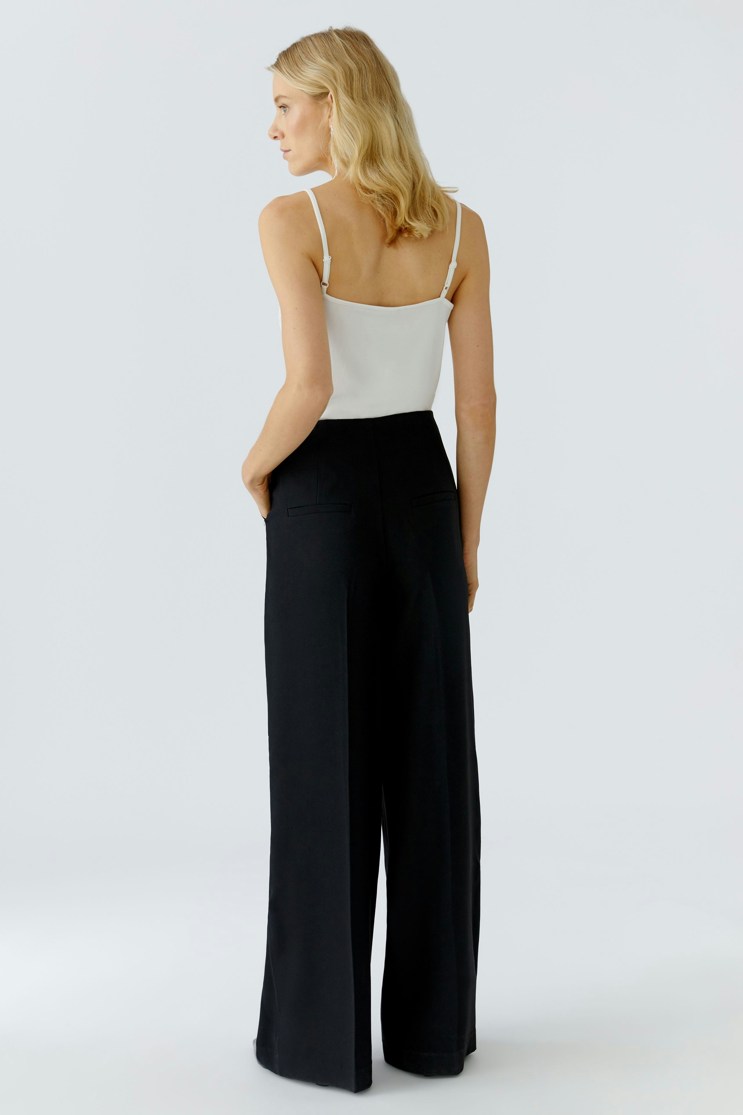 Stylish women's Marlene trousers: A woman in black wide-leg pants with a simple white top.