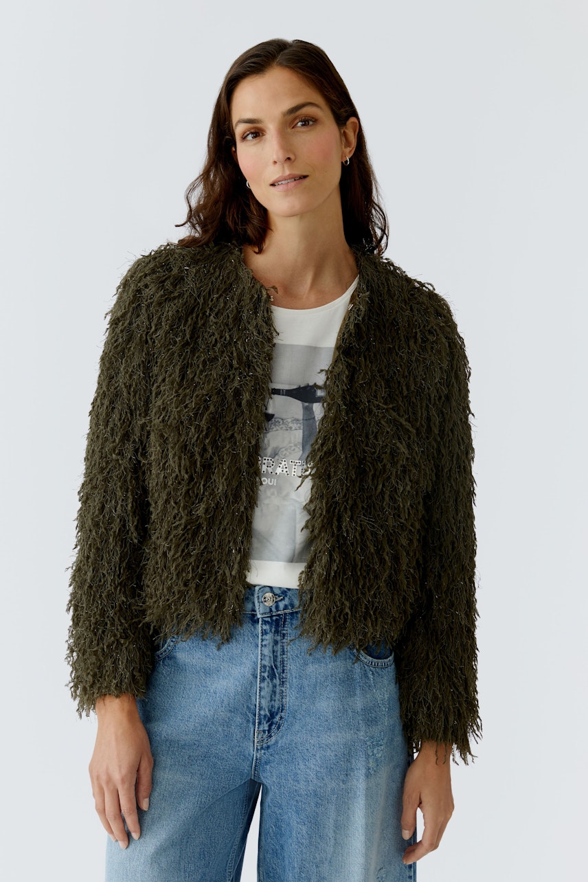 Flauschige Damen-Jacke: Frau trägt eine grüne, strukturierte Jacke über einem weißen T-Shirt und Jeans.