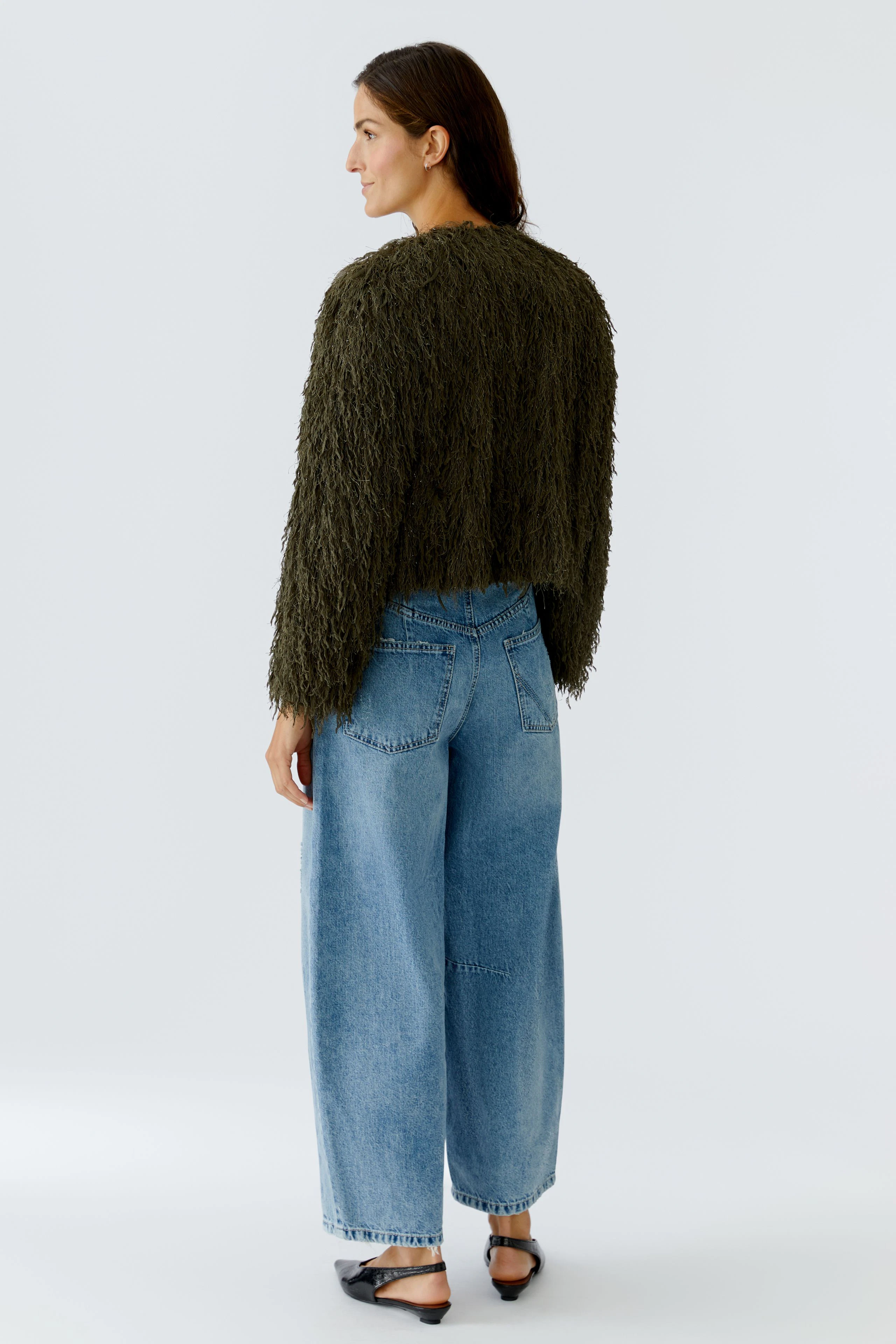 Damen-Jacke: Frau in einer lässigen, fransigen Jacke in Olivgrün mit weiten Jeans.