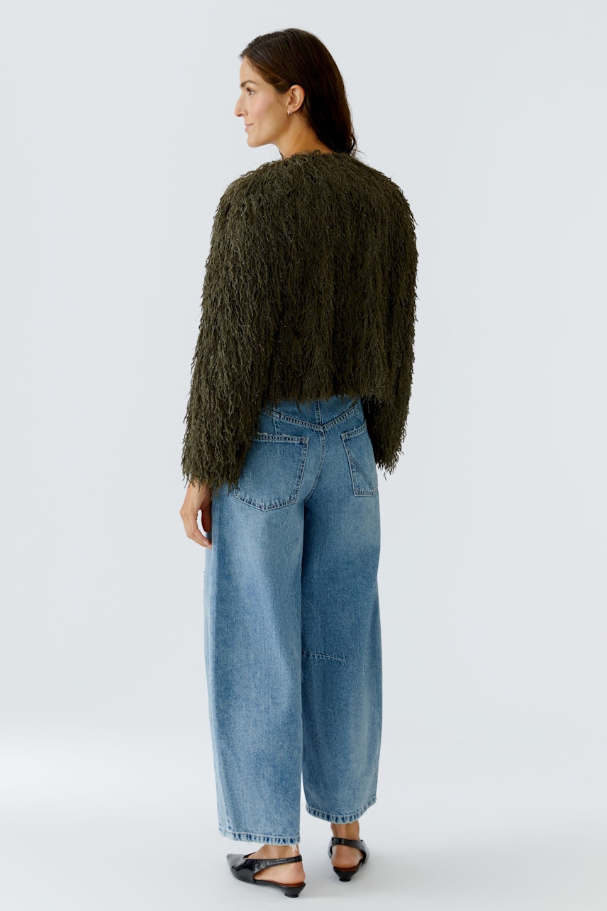 Damen-Jacke: Frau in einer lässigen, fransigen Jacke in Olivgrün mit weiten Jeans.