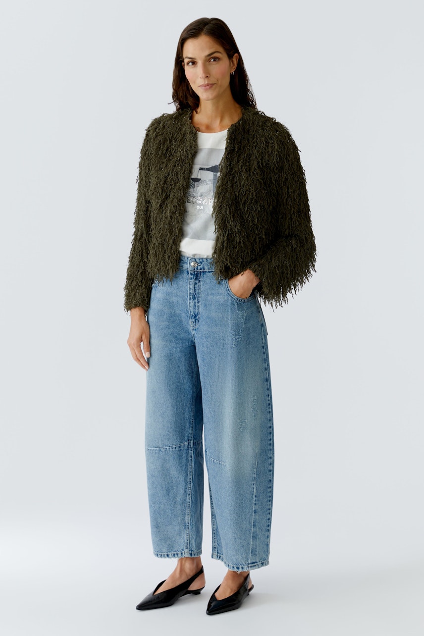 Damen-Jacke: Frau in einer flauschigen, olivgrünen Jacke kombiniert mit lässigen Jeans.