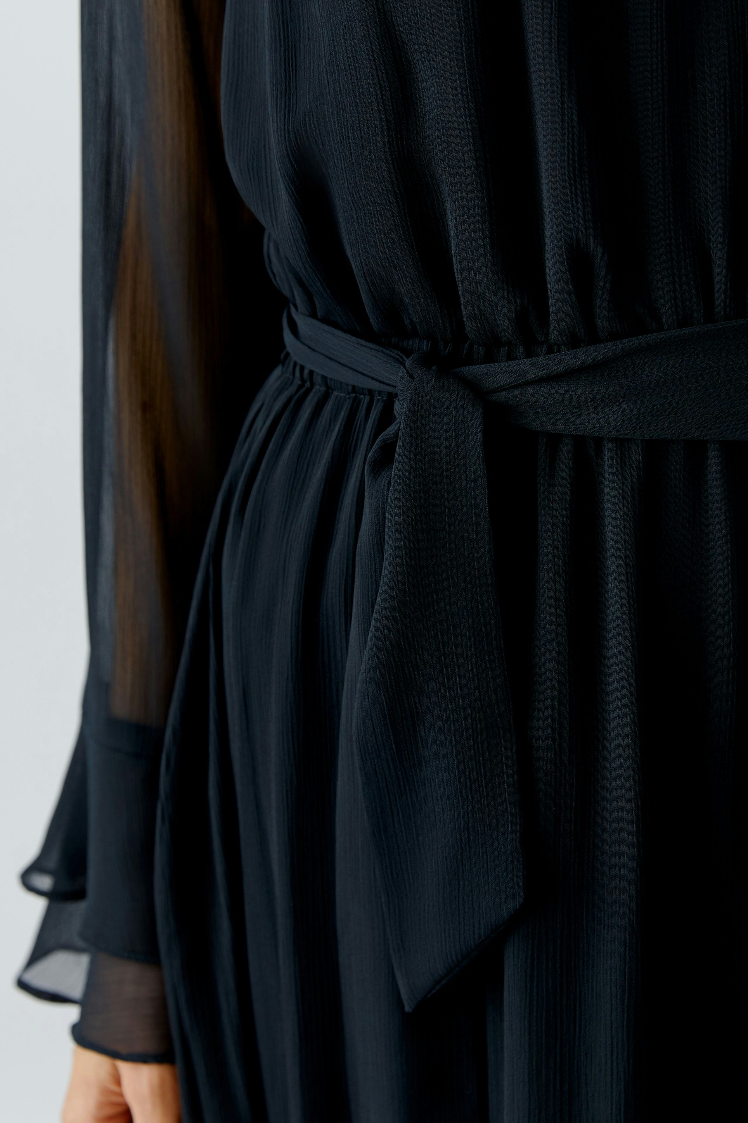Maxi dress: Woman in a flowing black dress with a tied waist, showcasing a relaxed style.