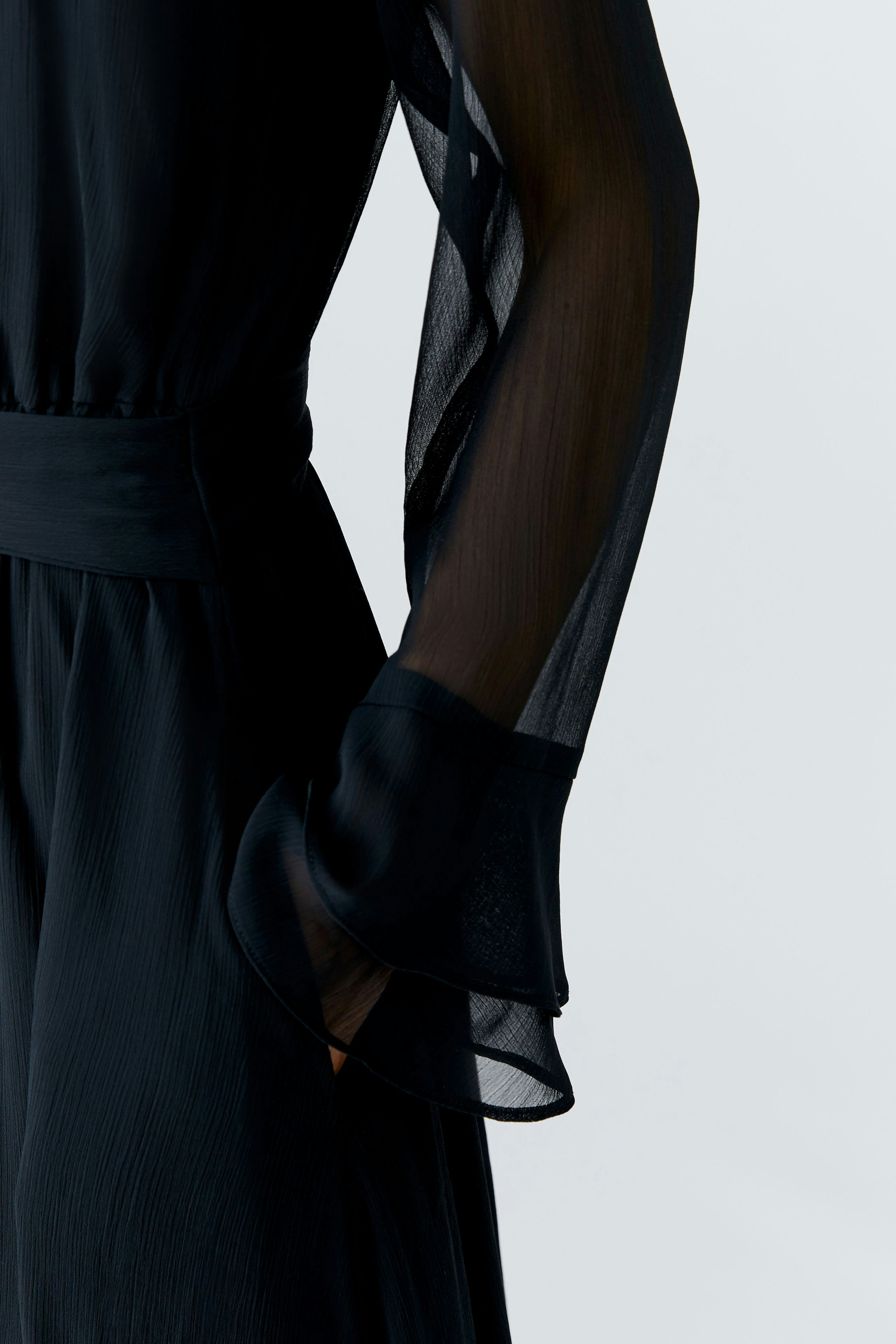 Stylish maxi dress: A woman in a flowing black maxi dress with sheer sleeves and a relaxed fit.