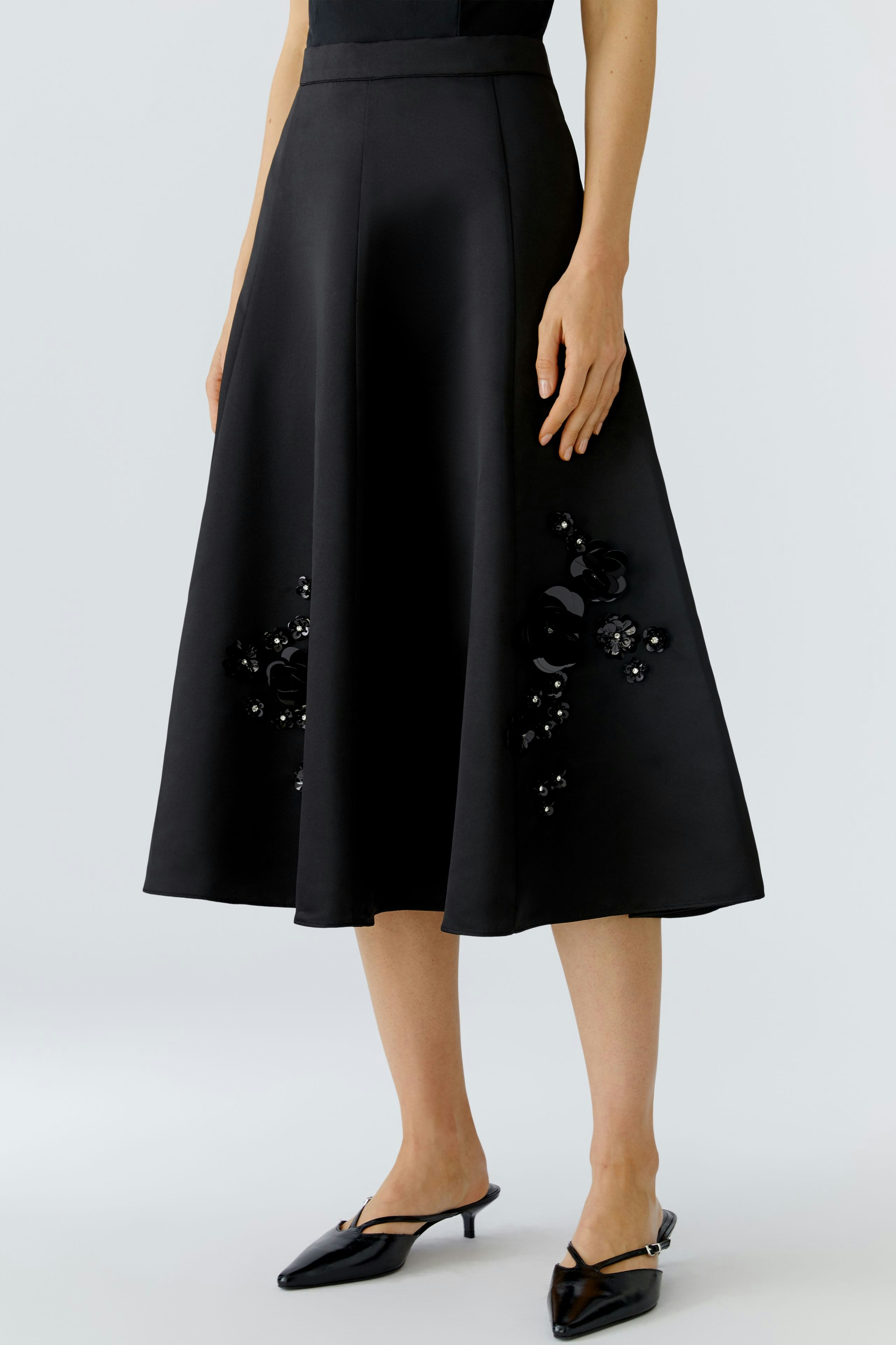 A-line skirt: Woman in a black skirt with floral embellishments, paired with stylish shoes.