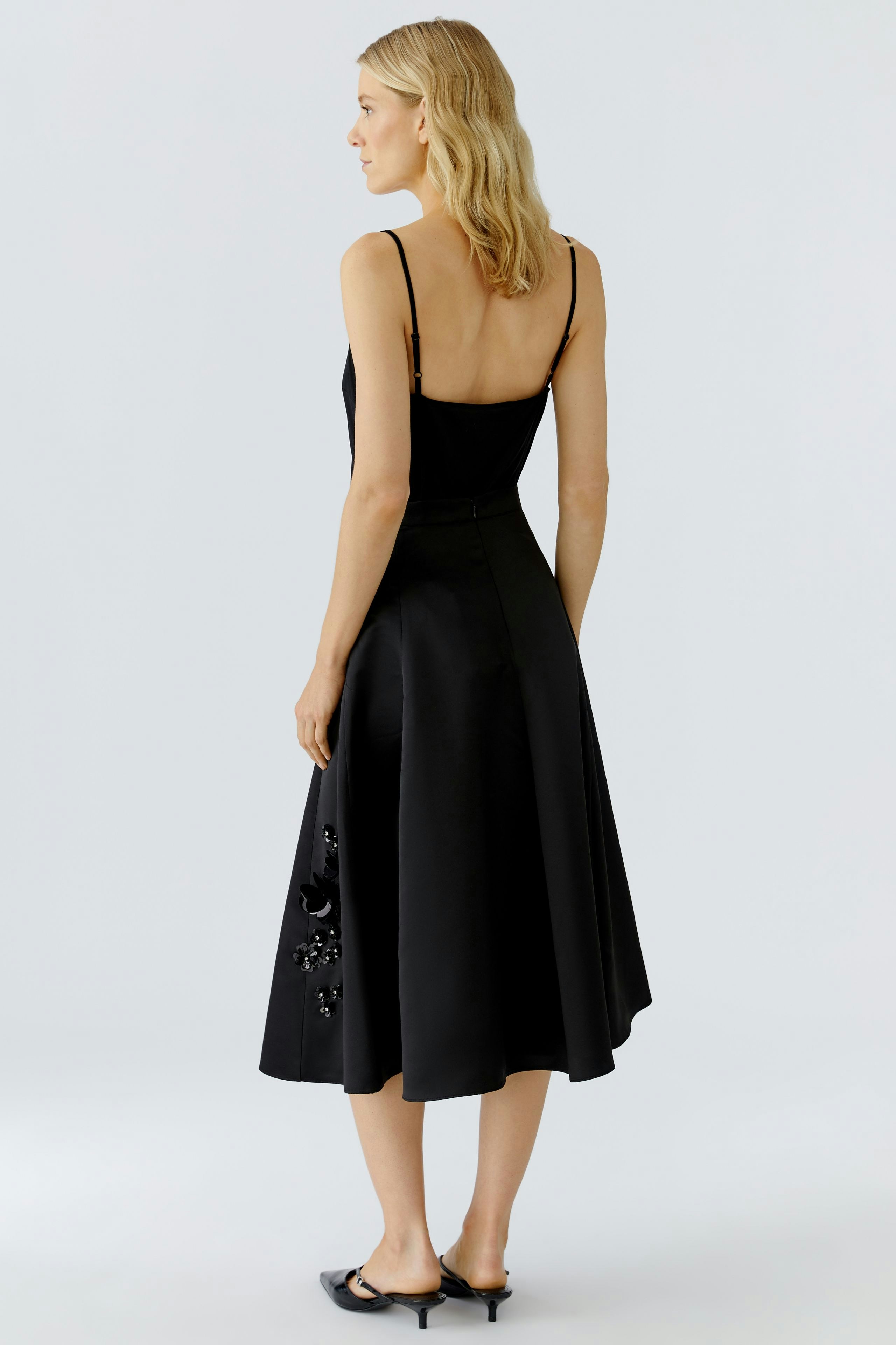 A-line skirt: Woman in a black A-line skirt with decorative details, showcasing a relaxed style.