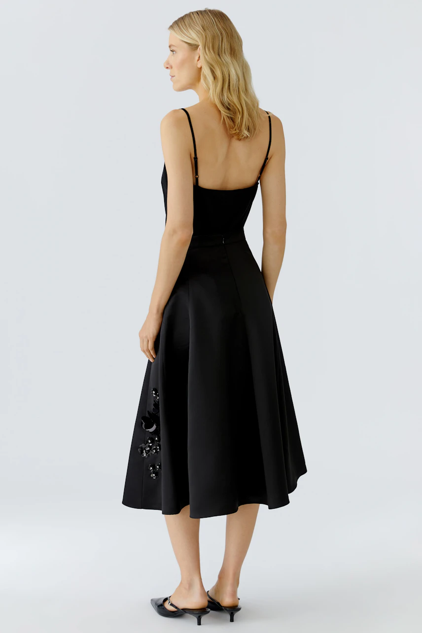 A-line skirt: Woman in a black A-line skirt with decorative details, showcasing a relaxed style.