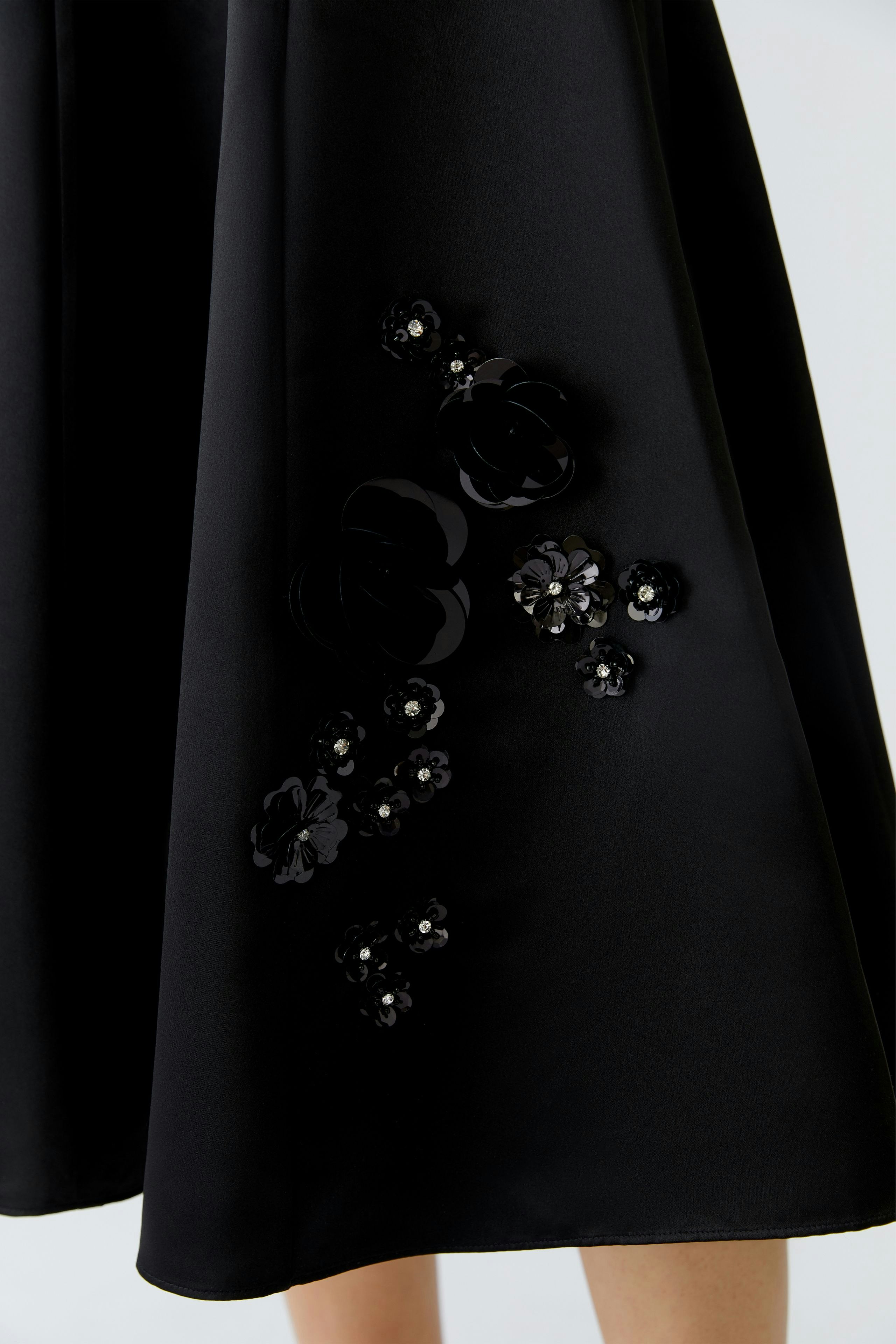 A-line skirt: Woman in a black skirt with floral embellishments, showcasing a stylish and casual look.