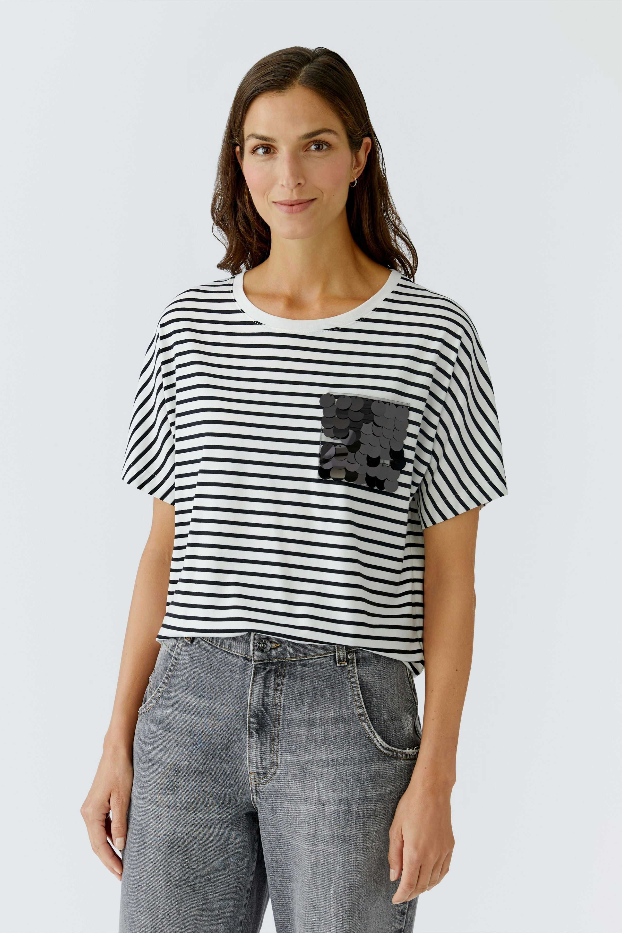 Casual women's T-shirt: A woman in a striped tee with a black pocket, paired with relaxed jeans.