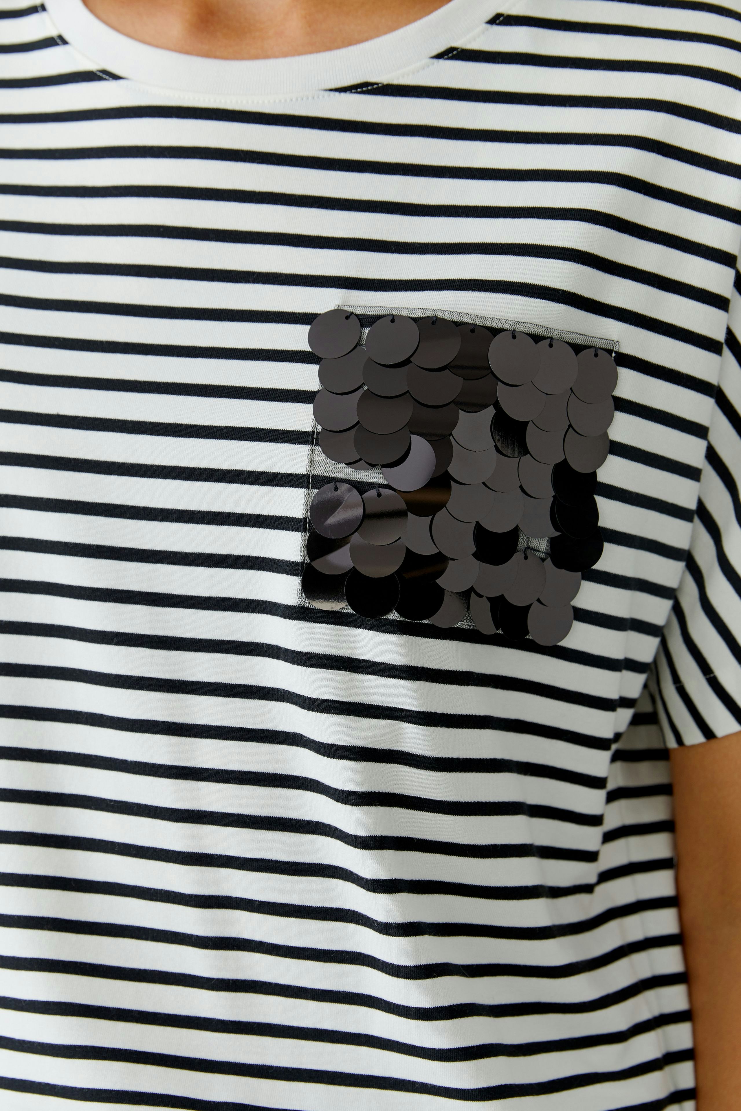 Casual women's T-shirt: Close-up of a striped tee with a sequined pocket detail.