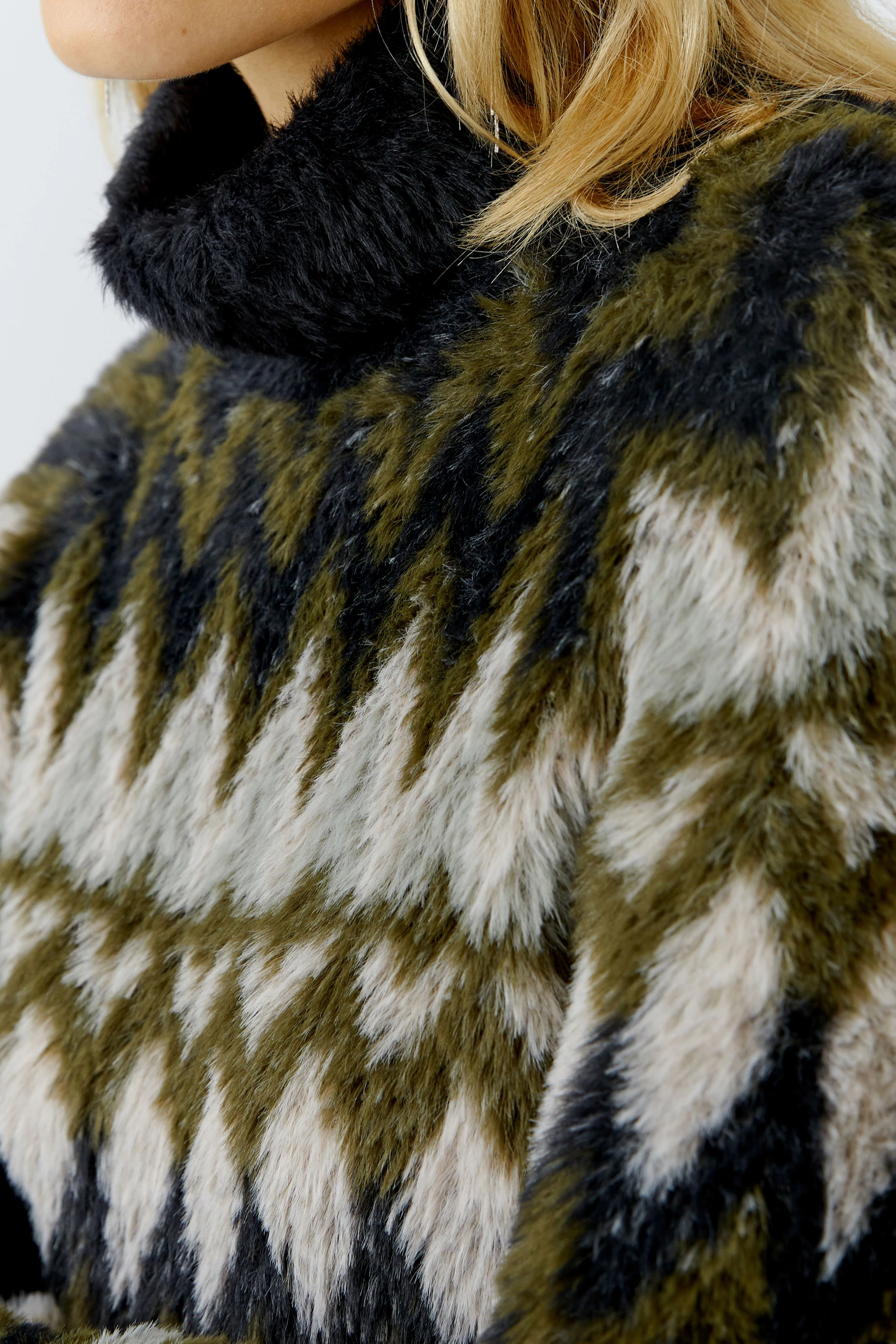 Gemütlicher Damen-Pullover: Frau trägt einen flauschigen Pullover mit geometrischem Muster in Erdtönen.