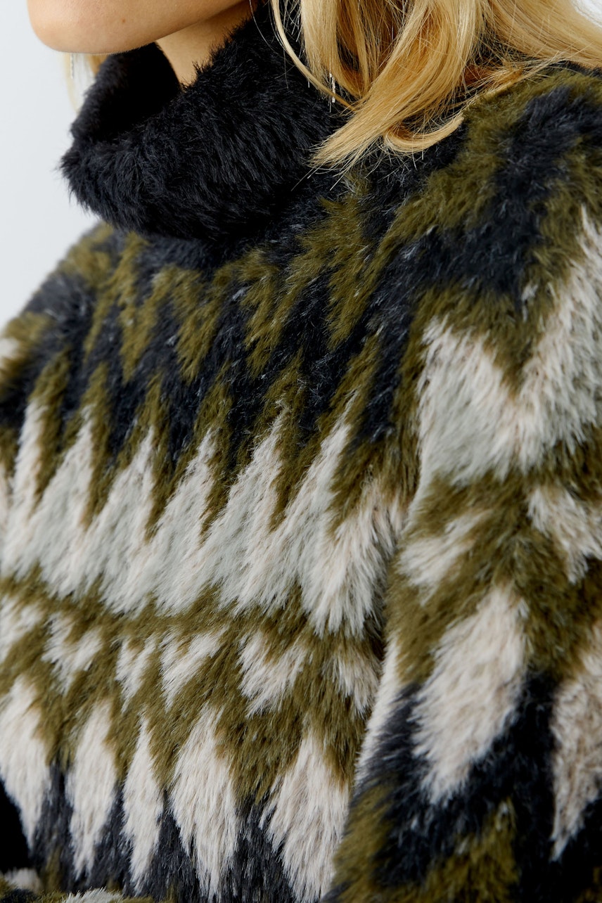 Gemütlicher Damen-Pullover: Frau trägt einen flauschigen Pullover mit geometrischem Muster in Erdtönen.