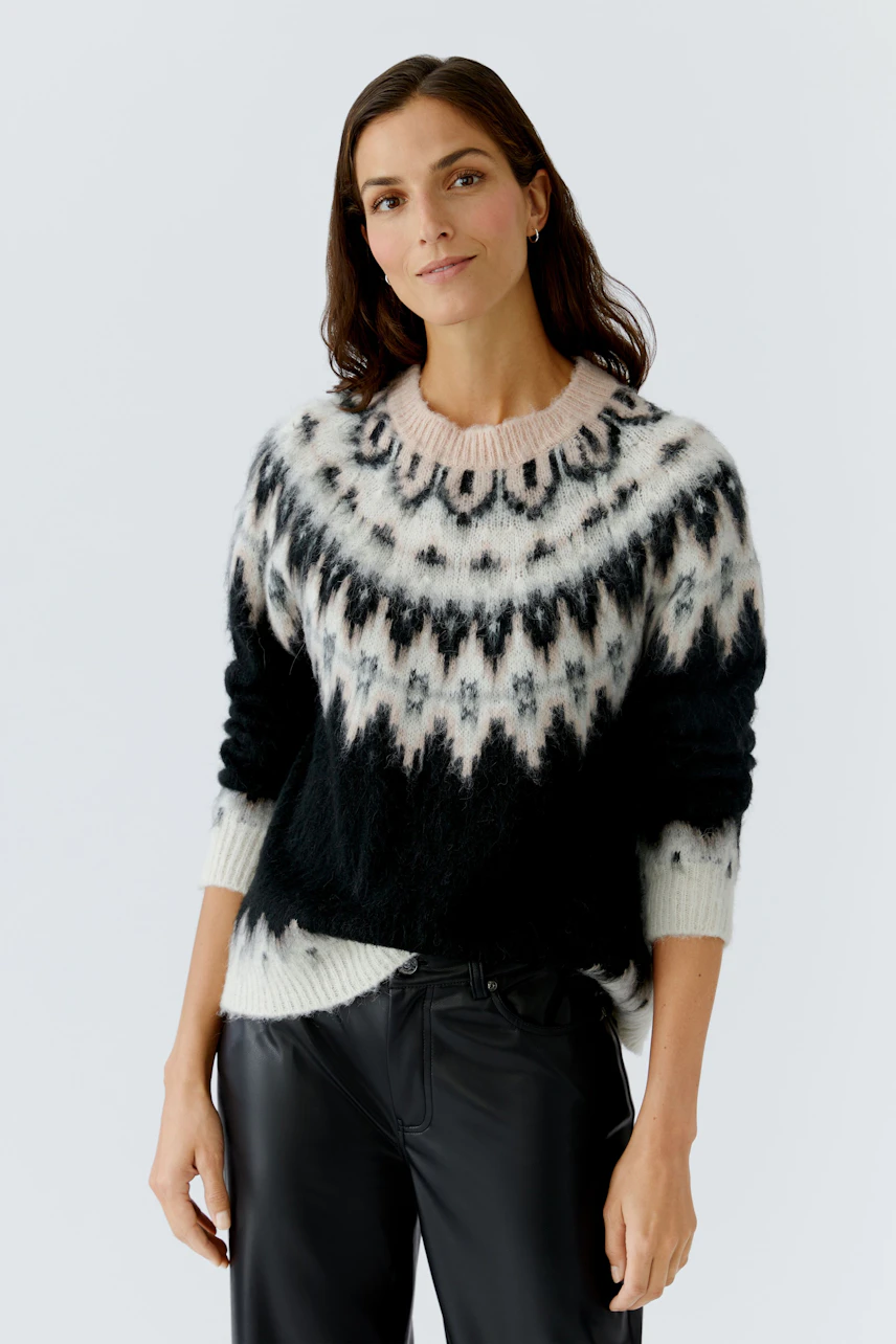 Damen-Pullover: Frau in schwarzem, gemustertem Strickpullover mit lässigem Schnitt und Rundhalsausschnitt.