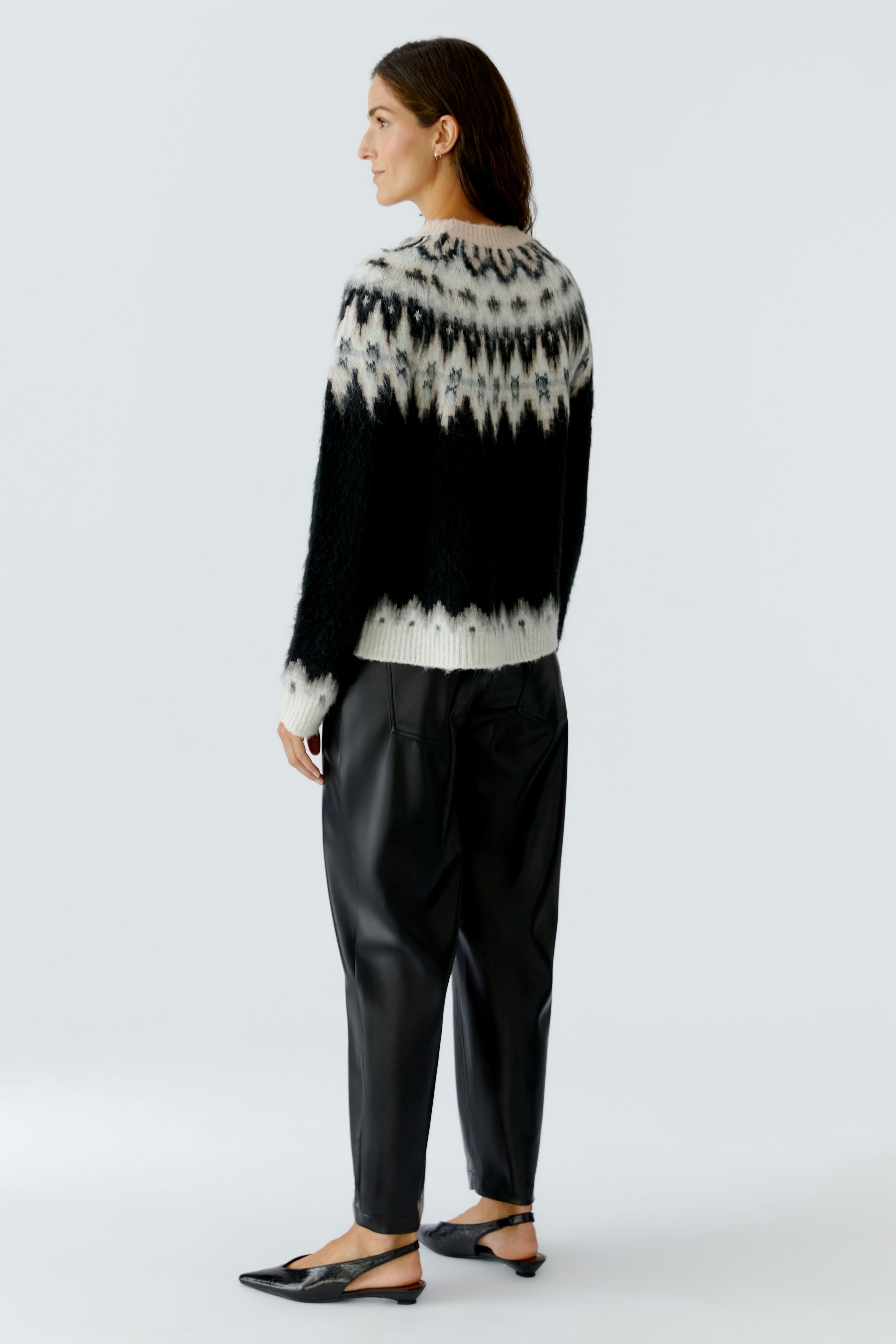 Damen-Pullover: Frau trägt einen kuscheligen, schwarz-weißen Strickpullover mit grafischem Muster.
