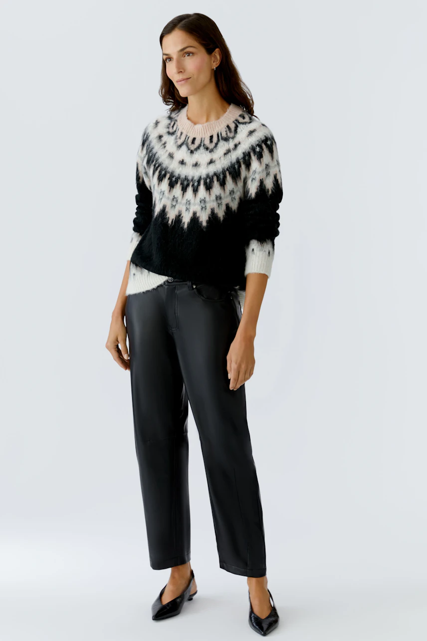 Damen-Pullover: Frau in schwarzem, gemustertem Strickpullover mit lässigem Schnitt und schwarzen Hosen.