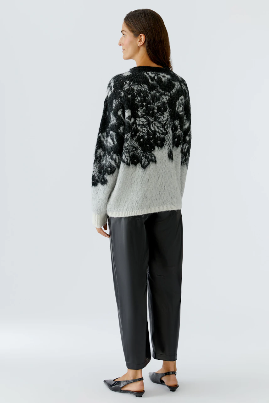 Damen-Pullover: Frau in grauem Pullover mit floralem Muster und lässigen Hosen von hinten.