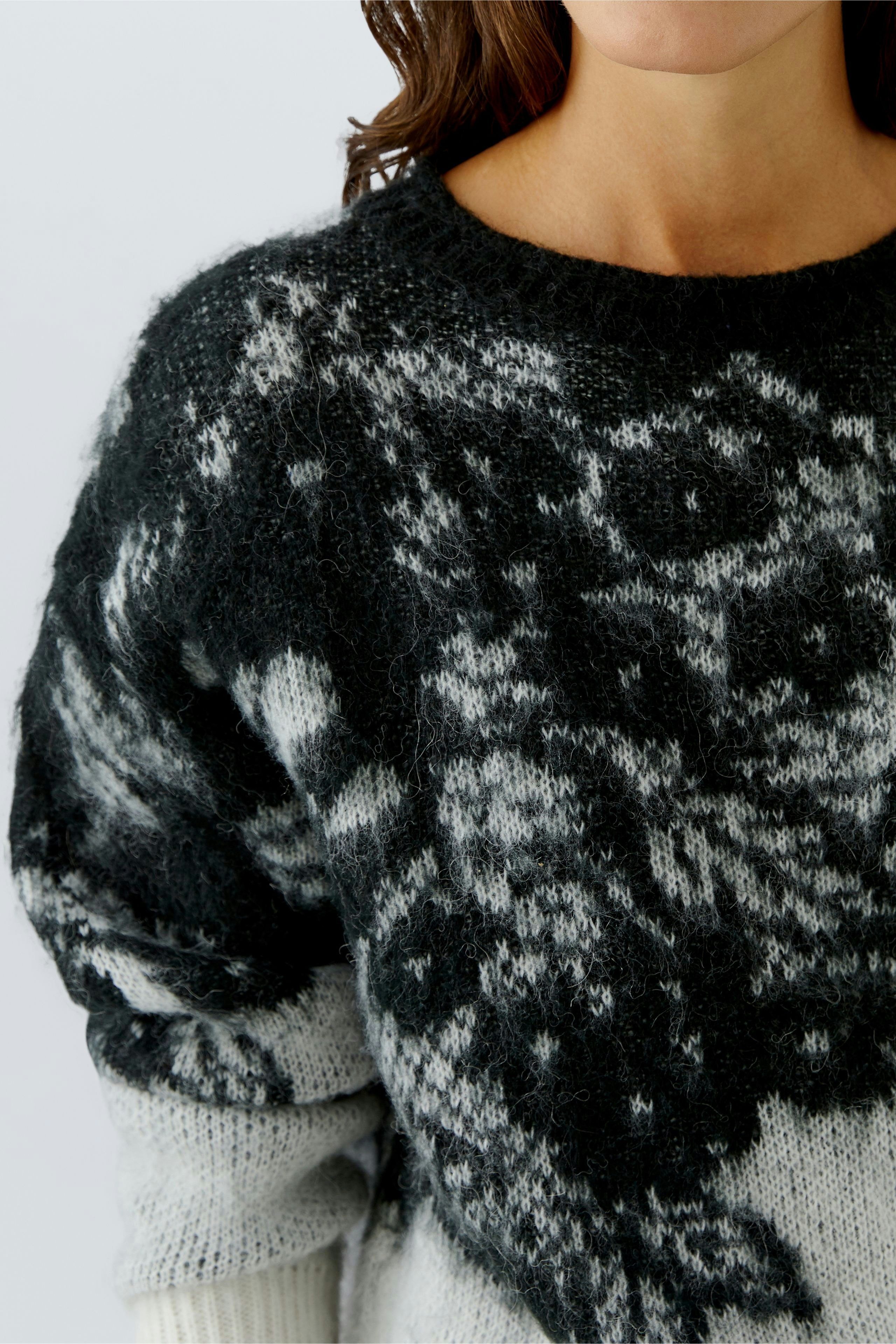 Casual women's pullover: Close-up of a woman in a cozy black and gray patterned pullover.