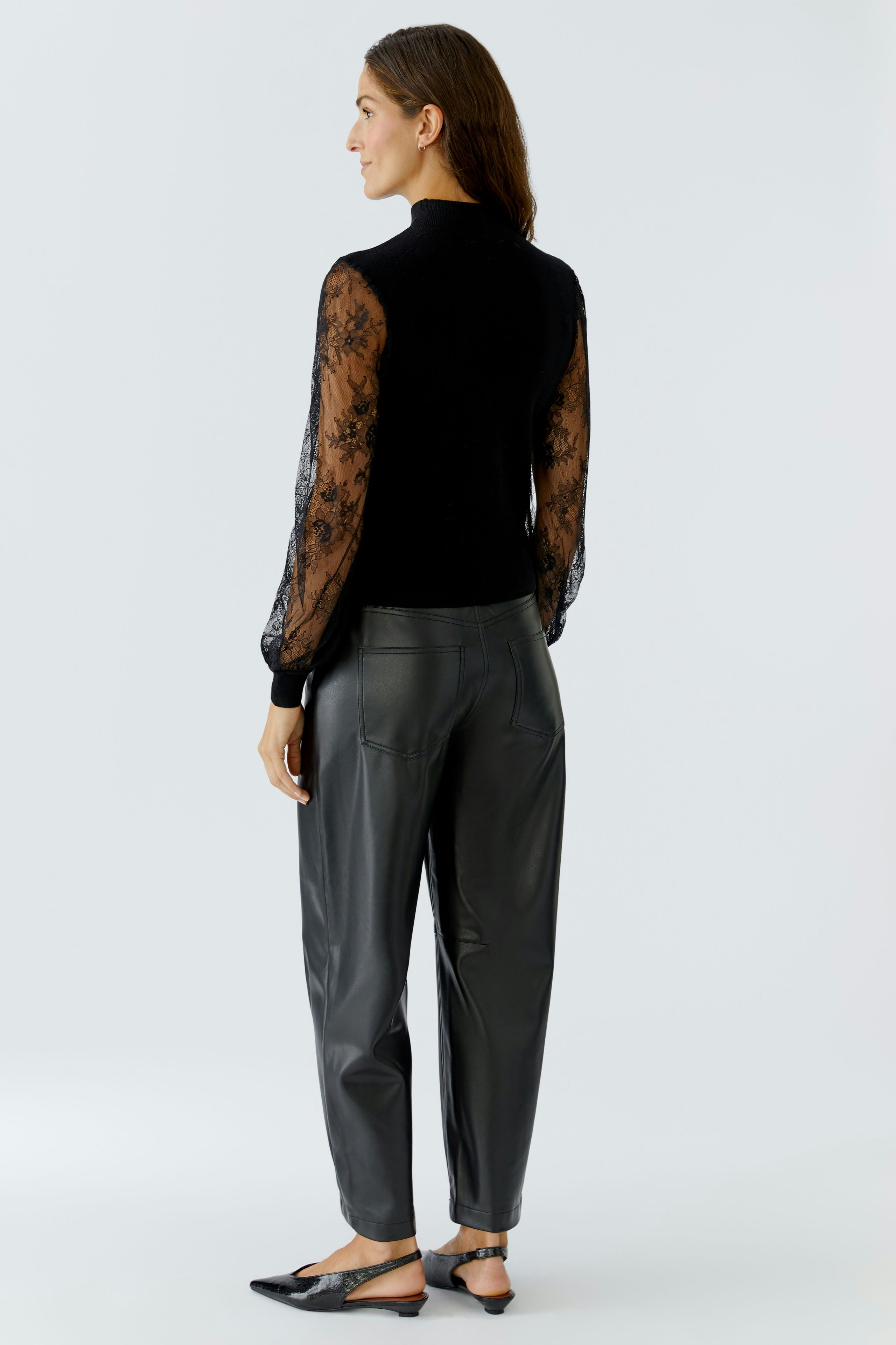 Stylish women's pullover with lace sleeves, paired with relaxed-fit trousers, showcasing a modern look.