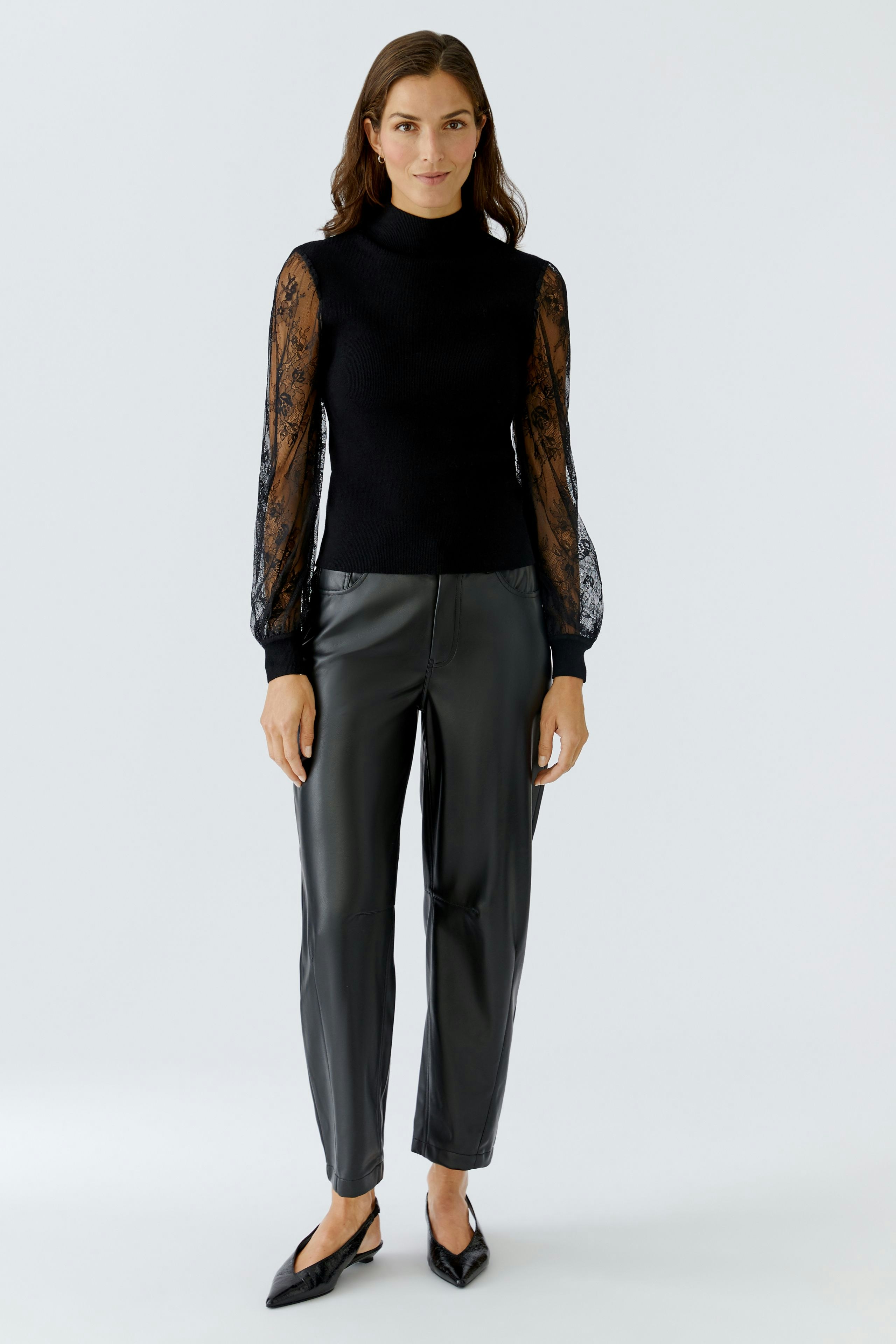 Modern women's pullover: A woman in a black pullover with lace sleeves and stylish pants.