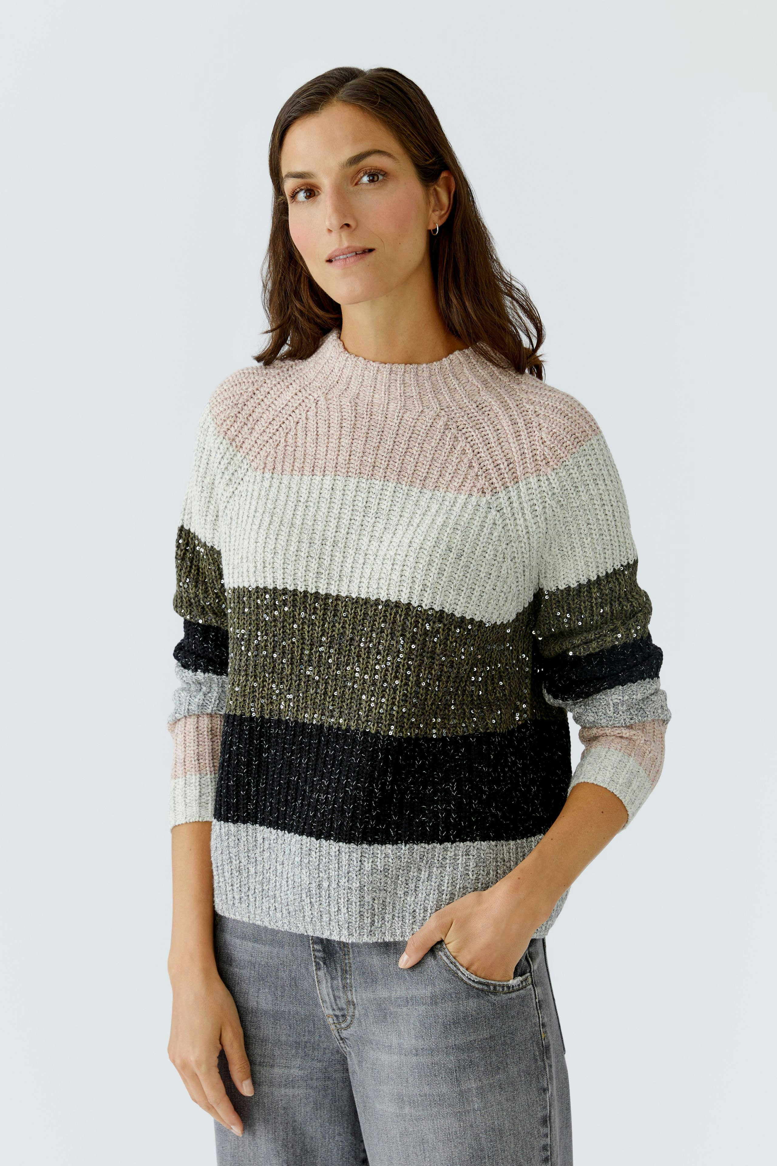 Casual women's pullover: Young woman in a striped knit pullover with sparkles, paired with jeans.